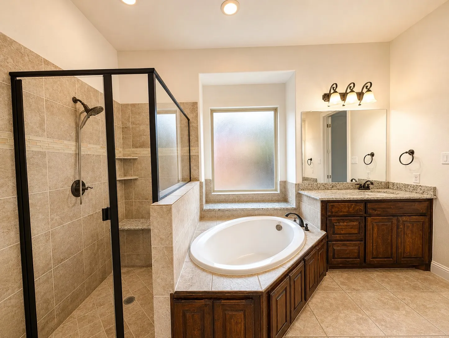 Bathroom featuring a frameless glass shower enclosure, built-in shower bench, garden tub, double vanity with stone countertops, and recessed lighting