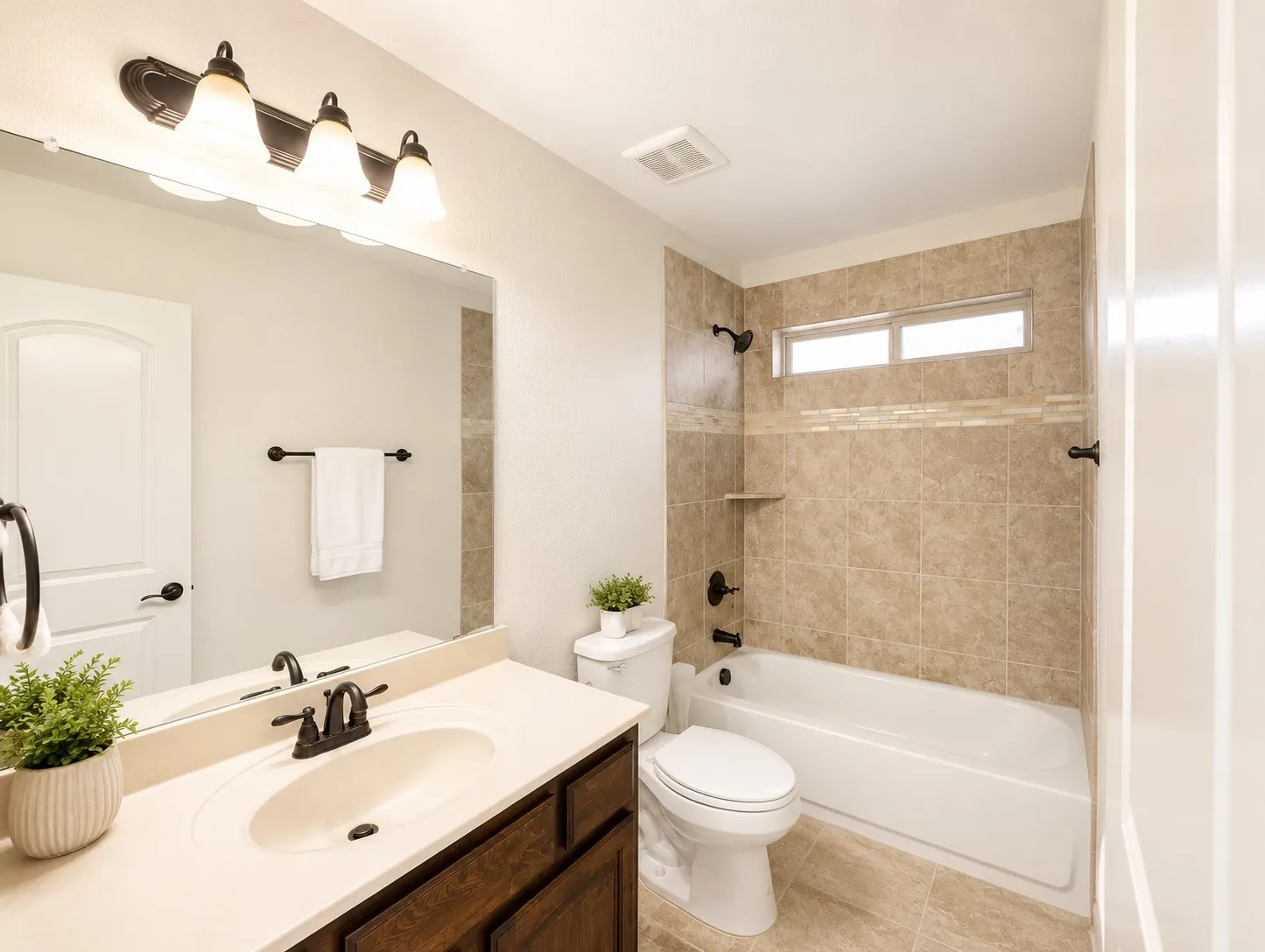 Bathroom featuring a single vanity with an integrated sink and dark wood-finish cabinetry, a full-width mirror, and an oil-rubbed bronze three-light fixture