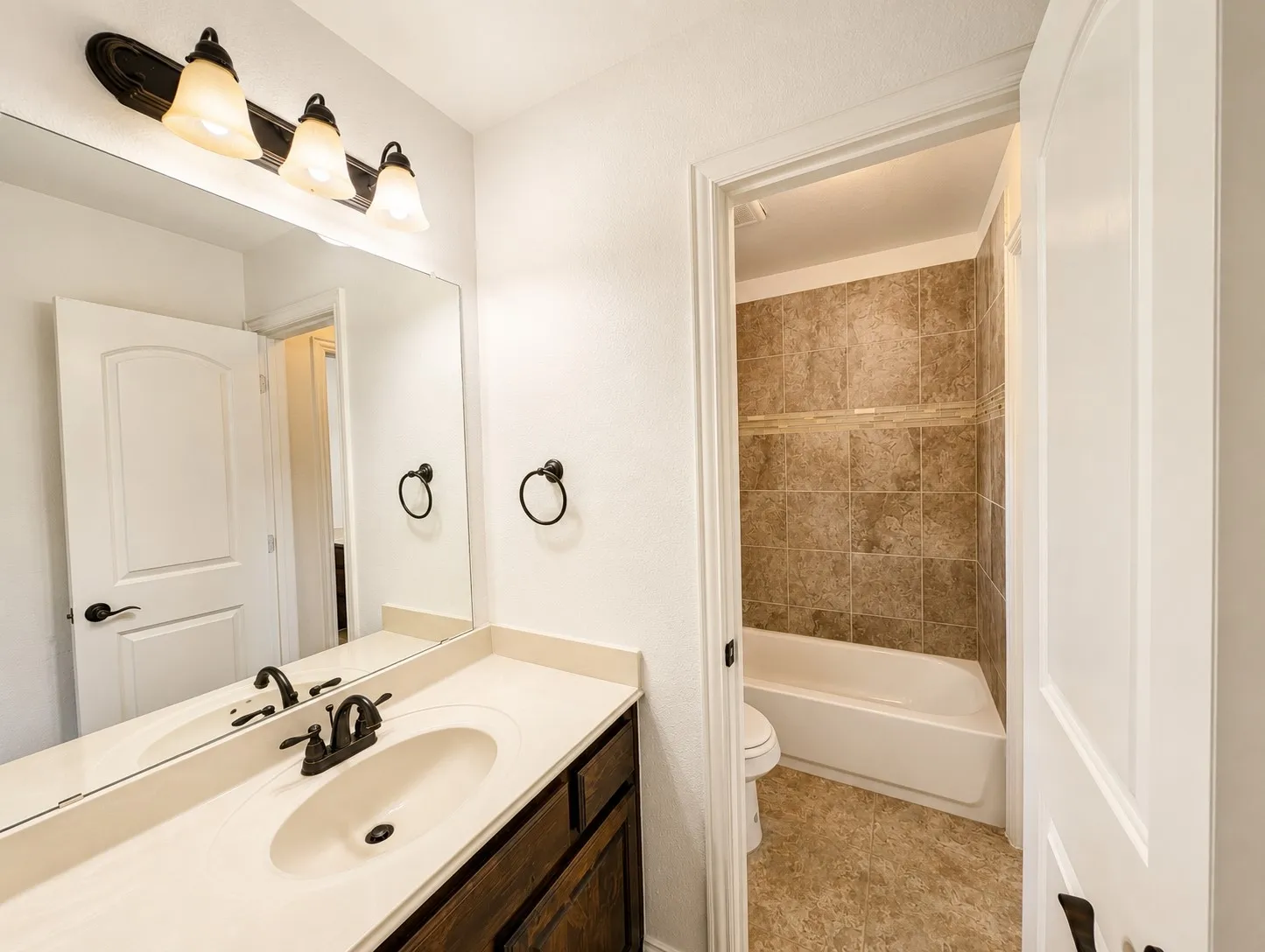 Bathroom vanity with a cream-toned countertop, integrated sink, and bronze-finish faucet