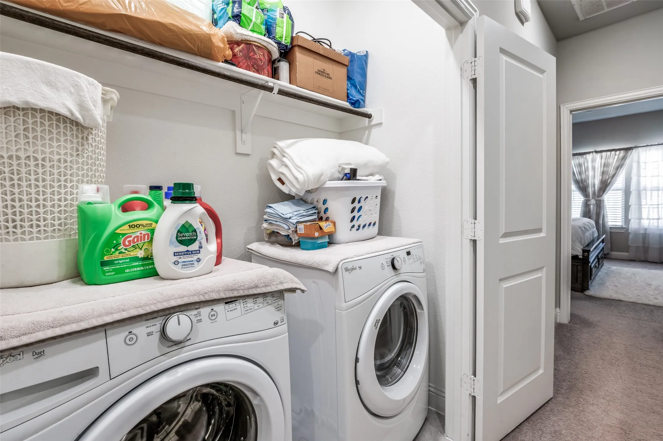 Dedicated laundry area featuring a built-in shelf, white walls, and a light-colored carpeted floor