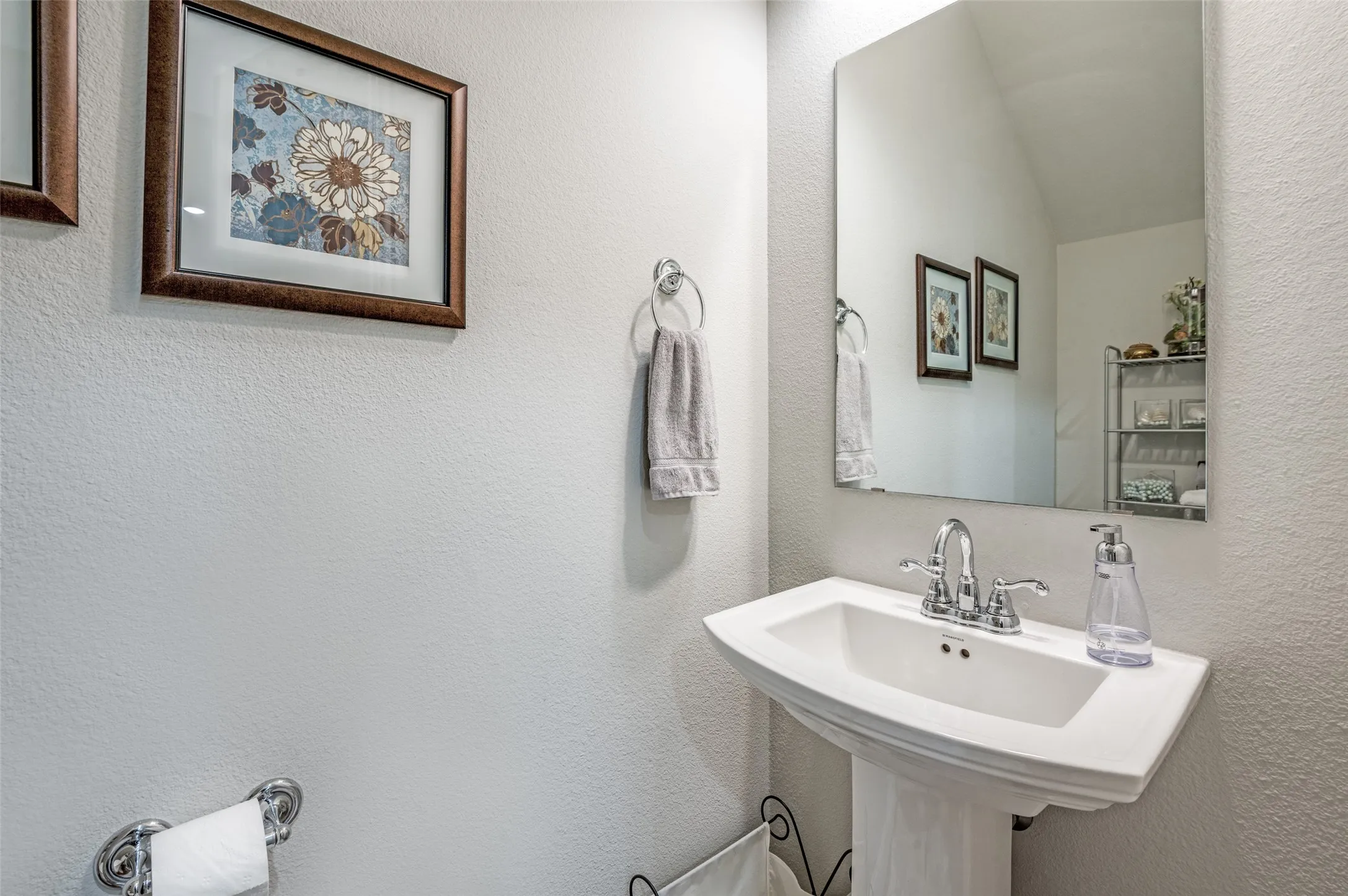 Pedestal sink with chrome fixtures and an expansive vanity mirror