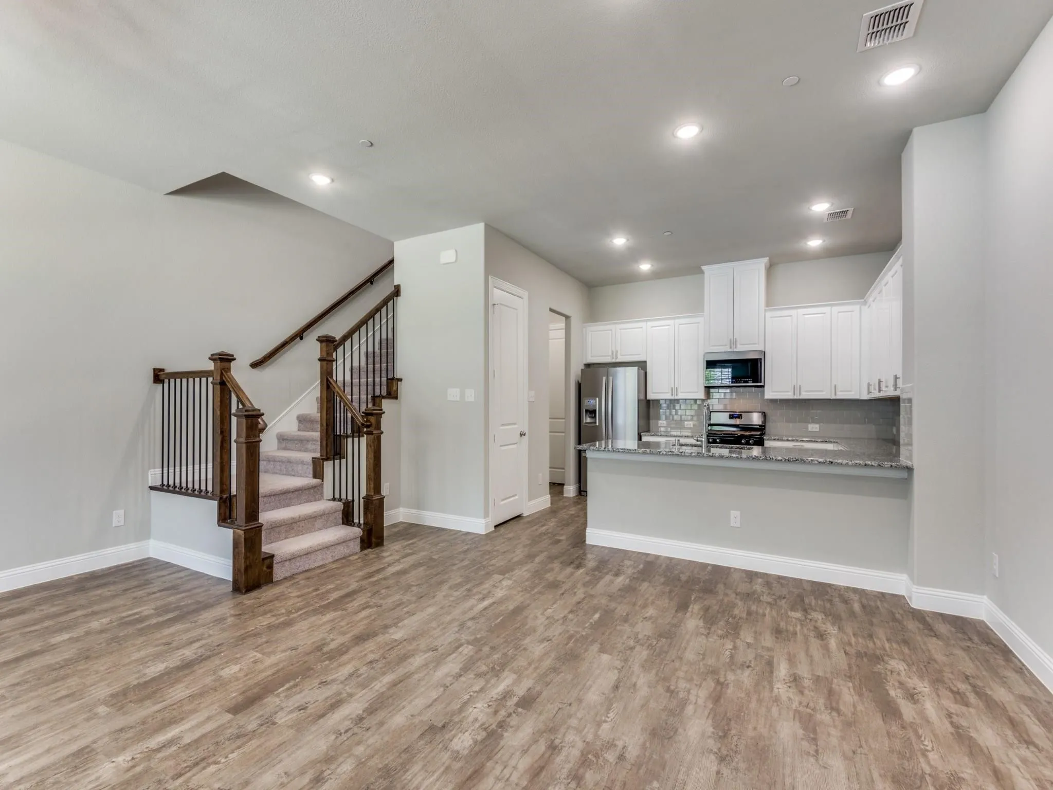 Open-concept living space featuring wood-finish flooring, recessed lighting, and a modern kitchen