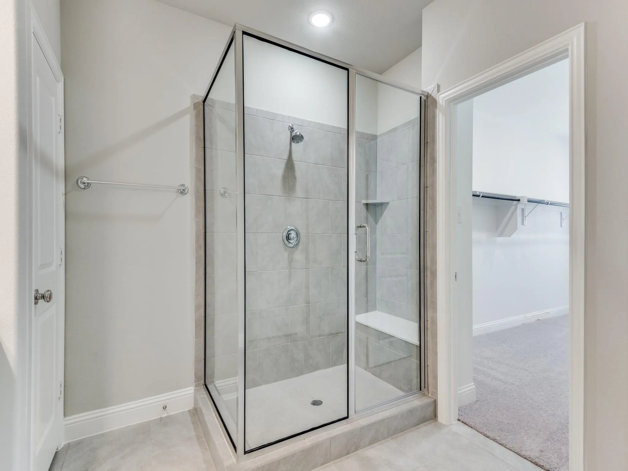 Walk-in shower with clear glass enclosure, a built-in bench, and a recessed wall niche