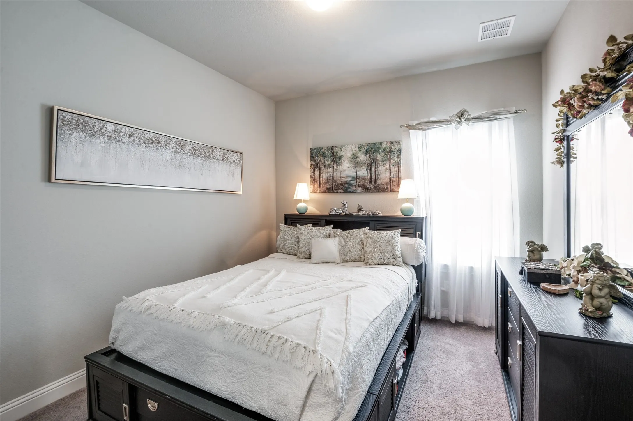 Light-filled interior space with a window featuring sheer white window treatments, light gray wall paint, and a textured carpet
