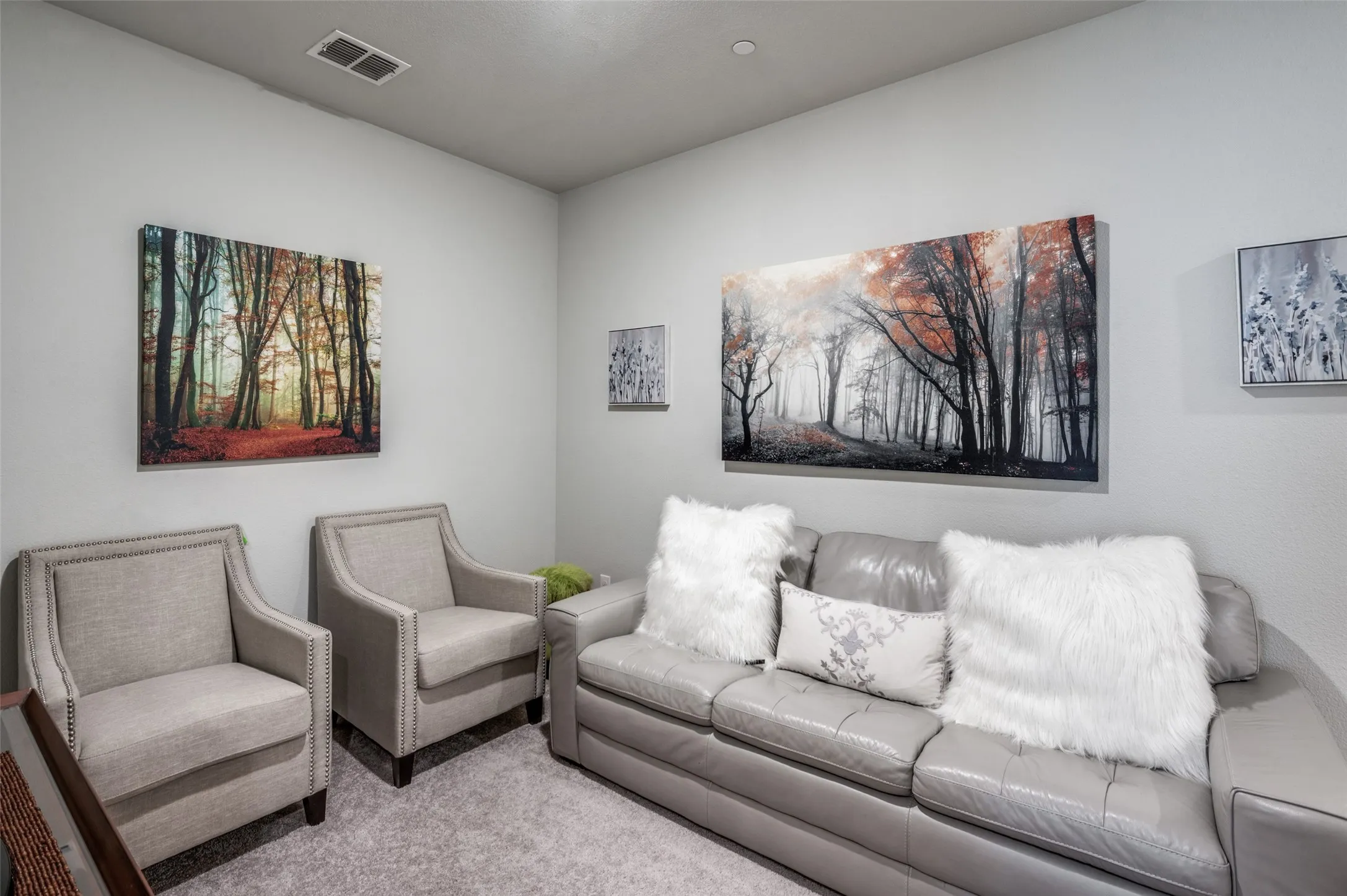 Recessed lighting illuminates a neutral-toned room featuring light gray walls, textured carpeting, and crown molding at the ceiling line