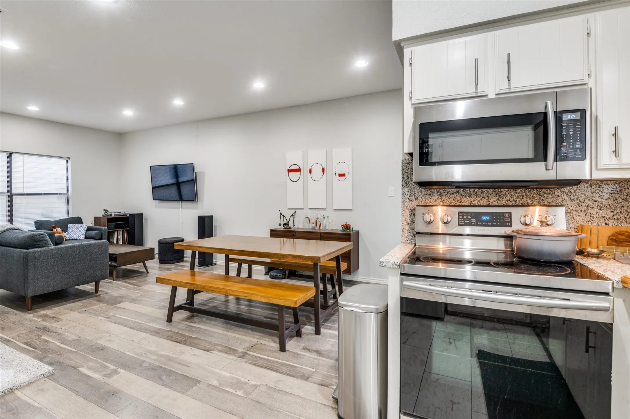 Modern kitchen featuring white cabinetry, stainless steel microwave, electric range, and light-toned granite countertops