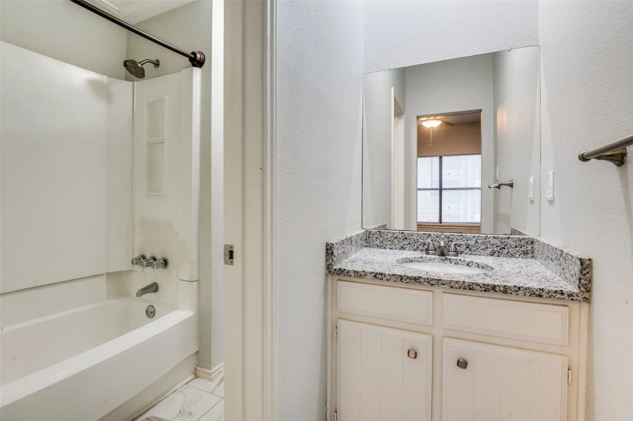Bathroom vanity with a granite-style countertop, undermount sink, and white cabinetry