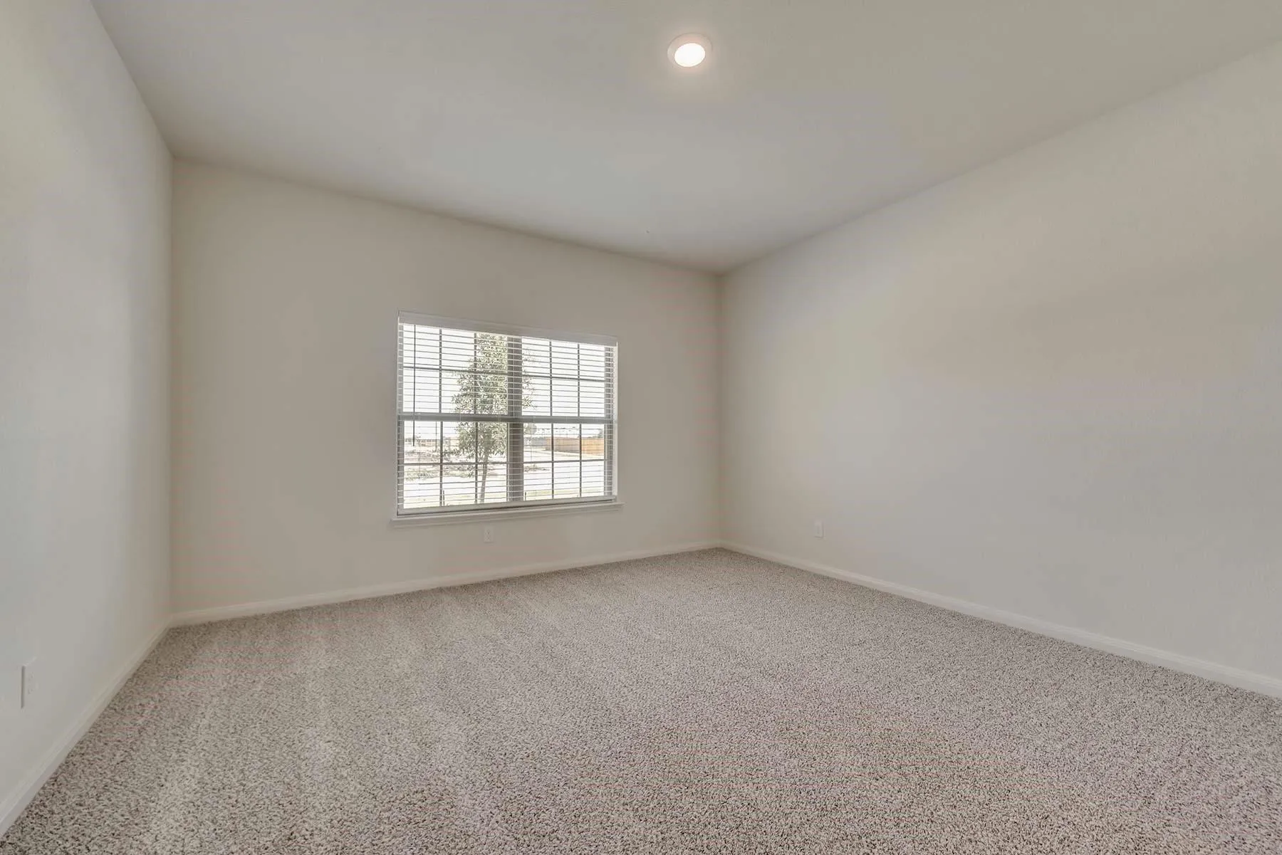 Carpeted room featuring a double-hung window with blinds, a vaulted ceiling, recessed lighting, and light-toned walls