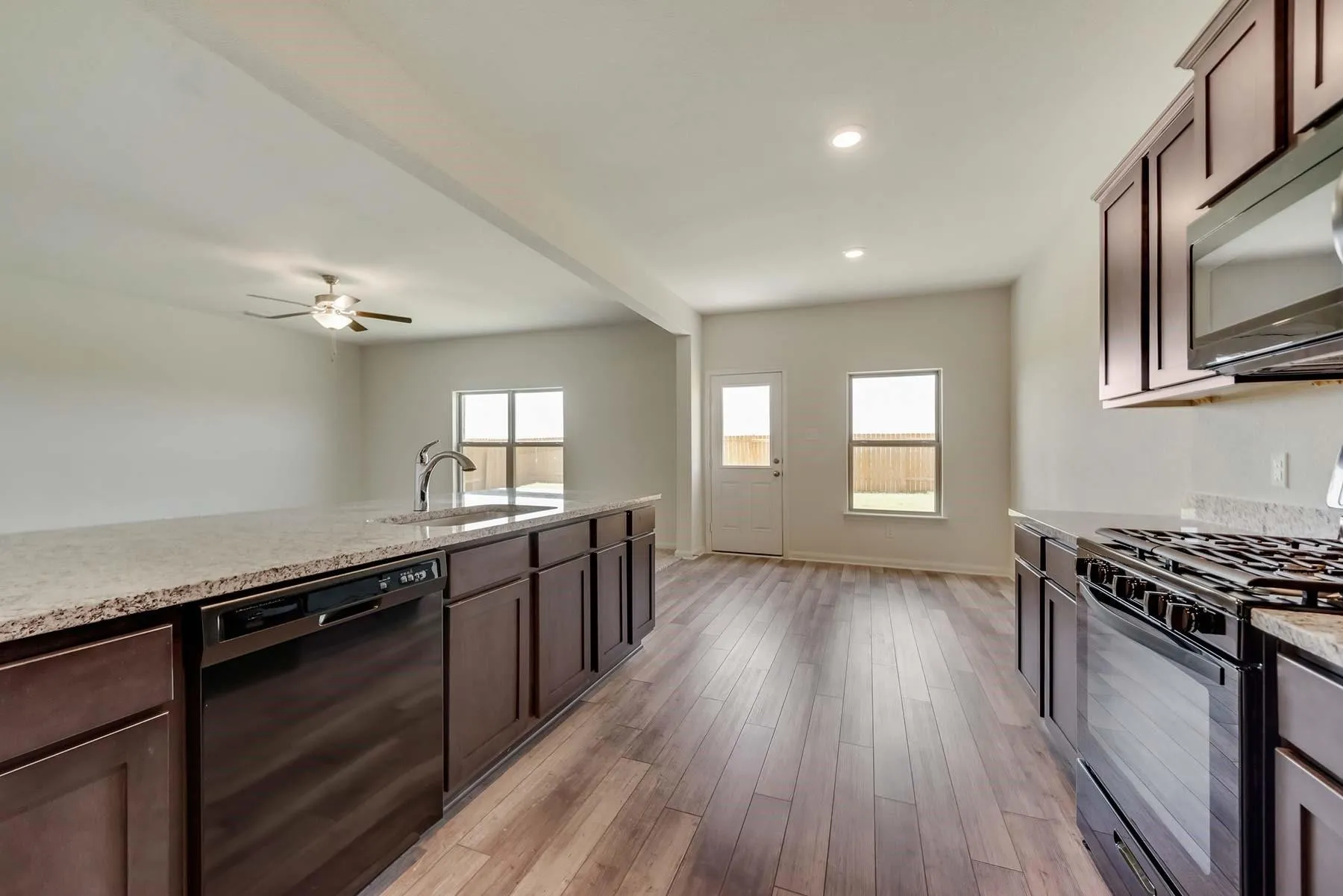 Kitchen featuring an island with built-in sink and stainless steel dishwasher, wood-finish flooring, recessed lighting, ceiling fan, and a gas range