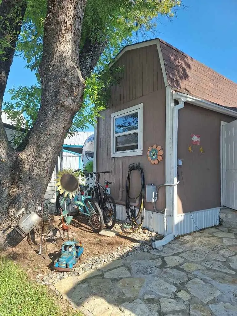 Lake side of well built solid shed. Large treee providing shade.