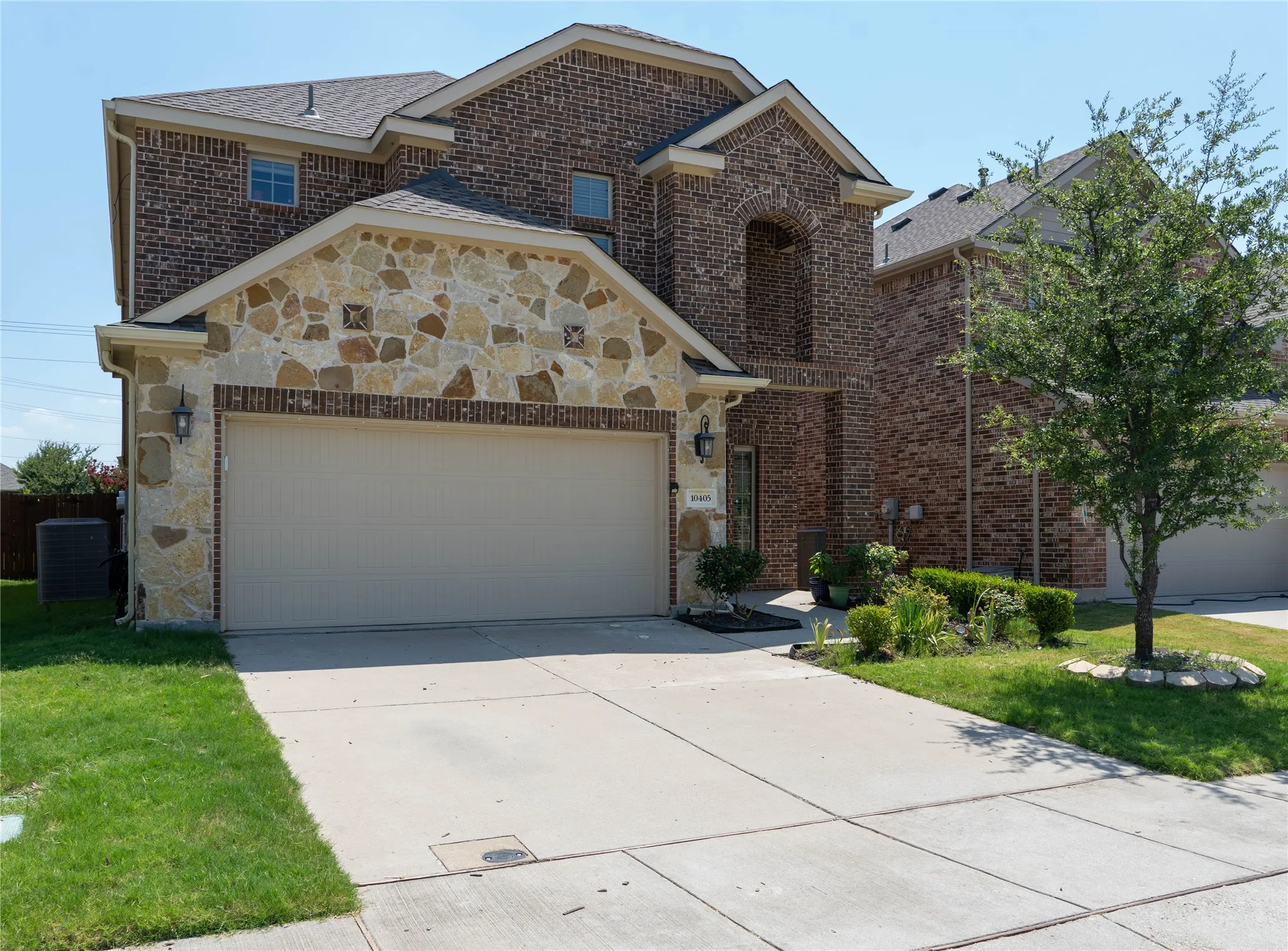 Front of property featuring a garage, central air condition unit, and a front lawn