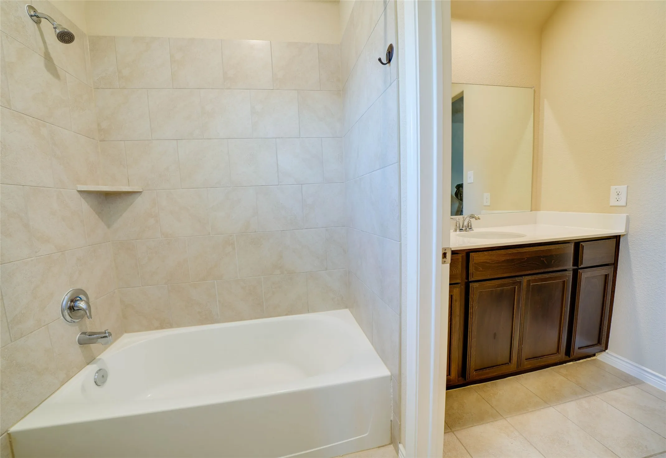 Bathroom featuring vanity, tiled shower / bath combo, and tile patterned floors