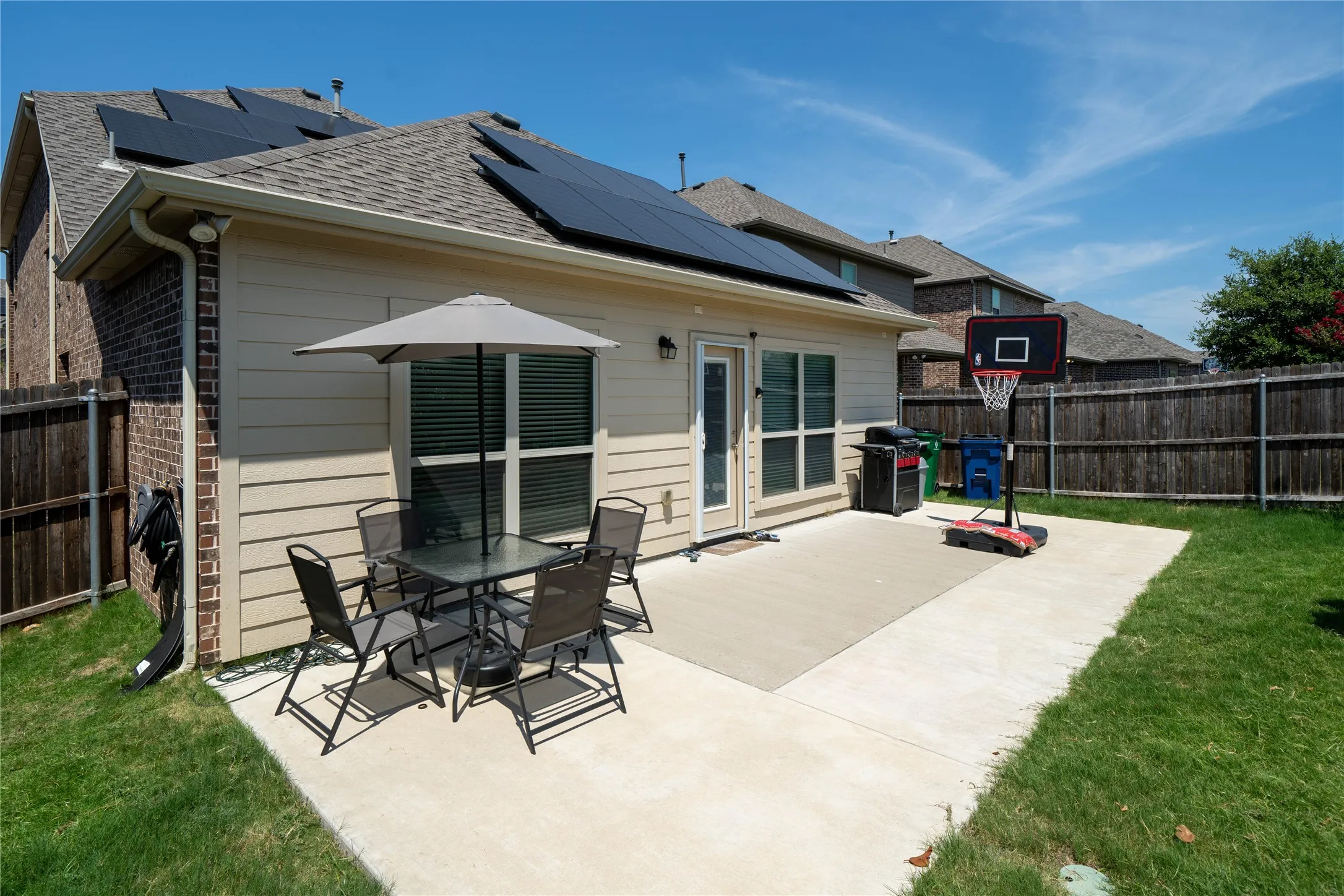 Rear view of property featuring a patio, a lawn, and solar panels