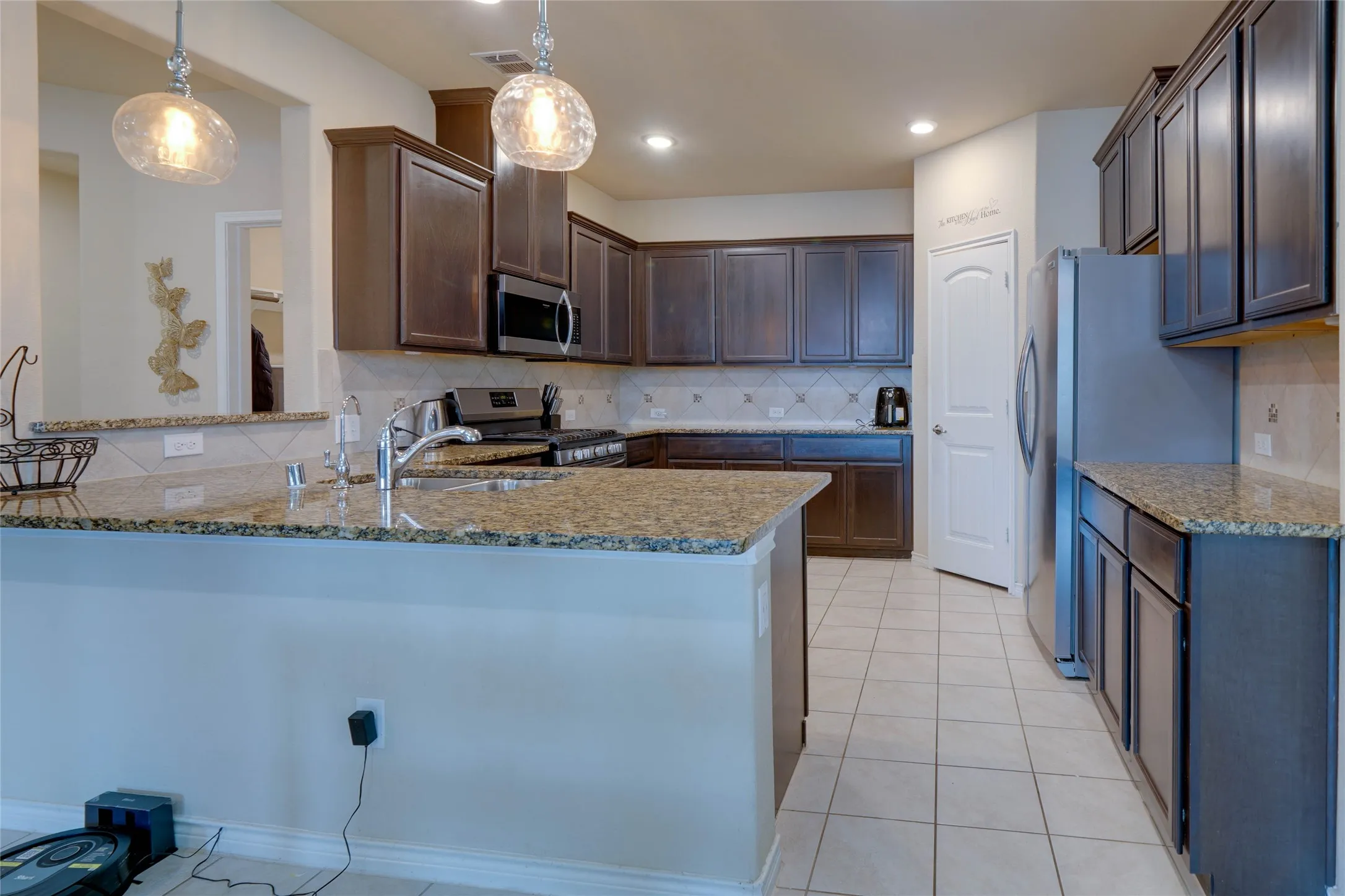 Kitchen with pendant lighting, kitchen peninsula, tasteful backsplash, and stainless steel appliances