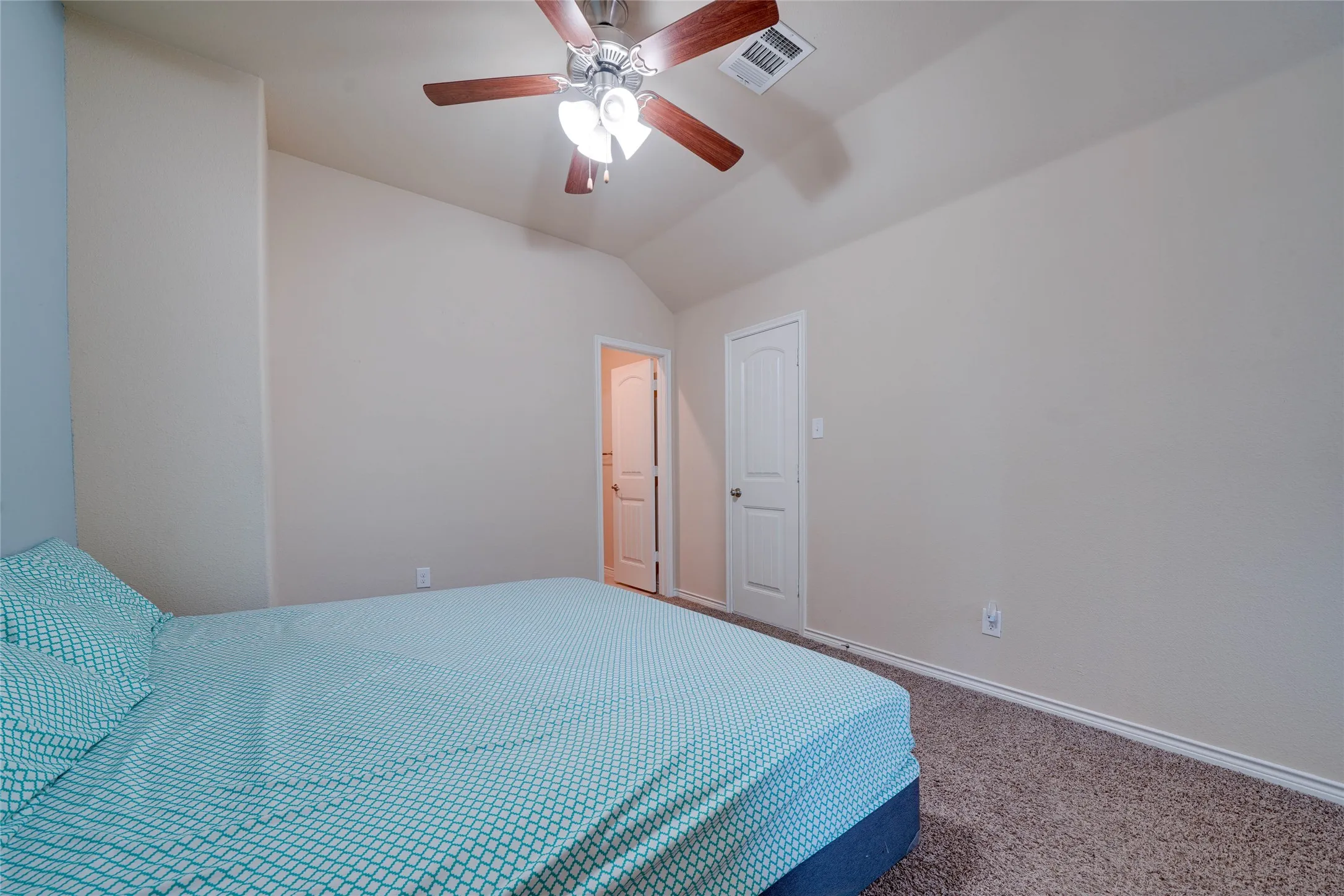 Carpeted bedroom with ceiling fan and vaulted ceiling
