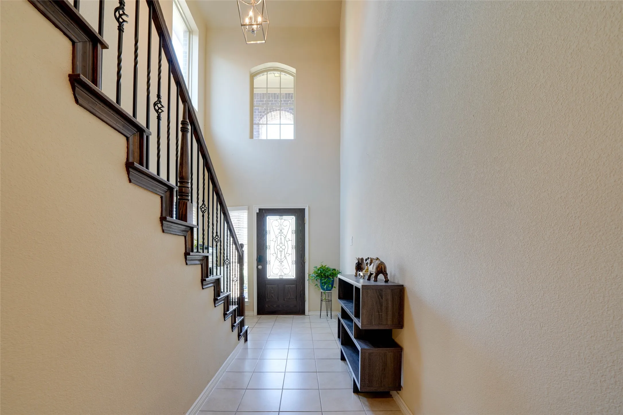 Tiled foyer featuring a towering ceiling and a chandelier