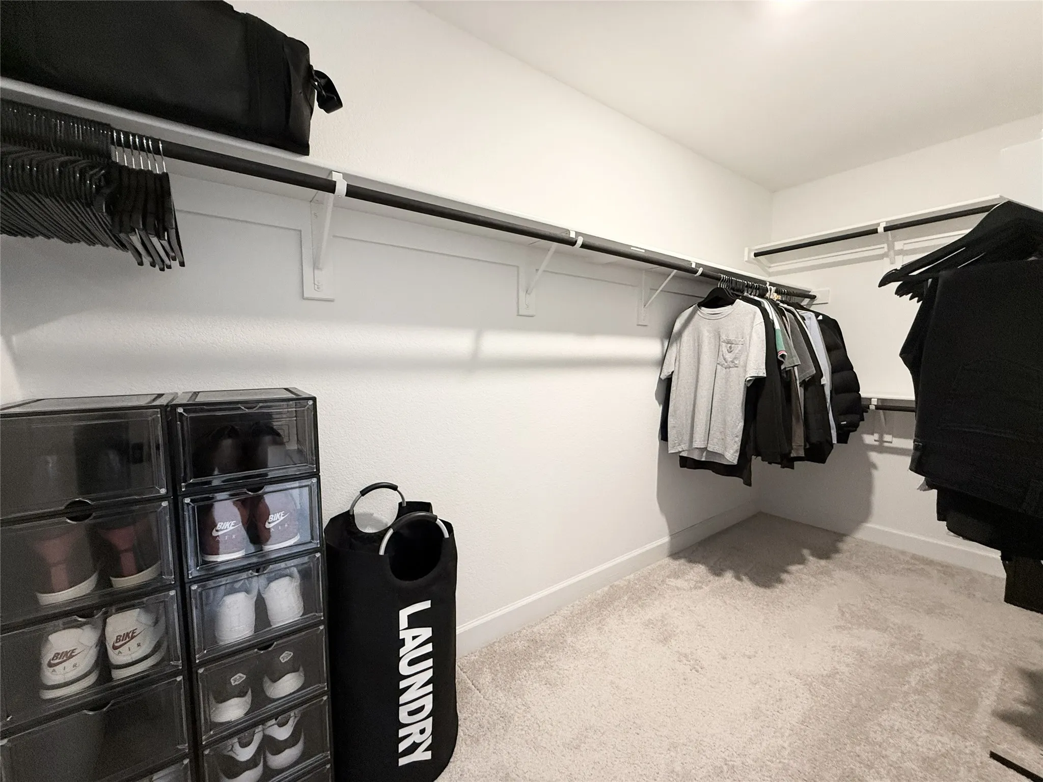 Walk-in closet featuring light-toned carpeting, white walls, and multiple levels of built-in shelving and hanging rods