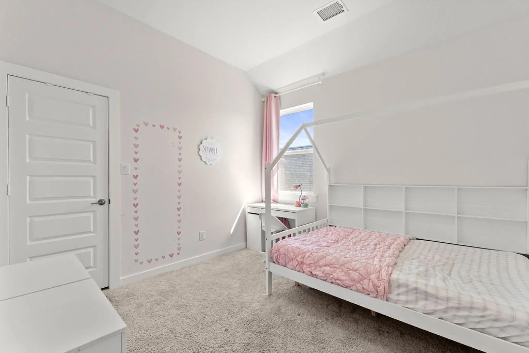 Carpeted room featuring a window with natural light, a five-panel interior door, and built-in shelving along one wall