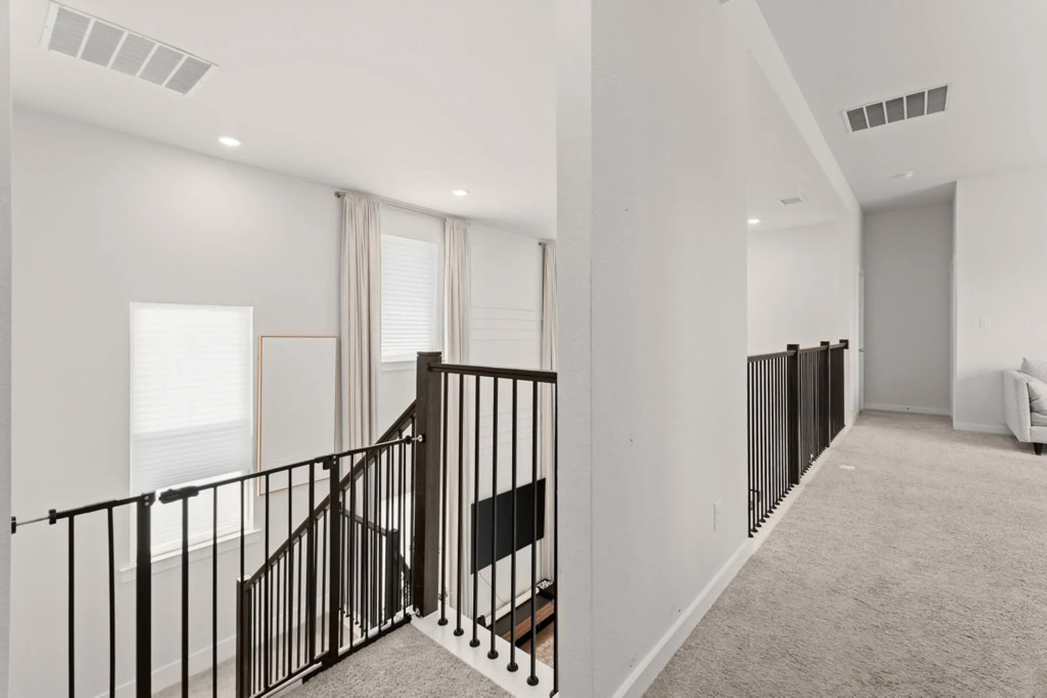 Upper-level hallway featuring light carpeting, recessed lighting, and white walls