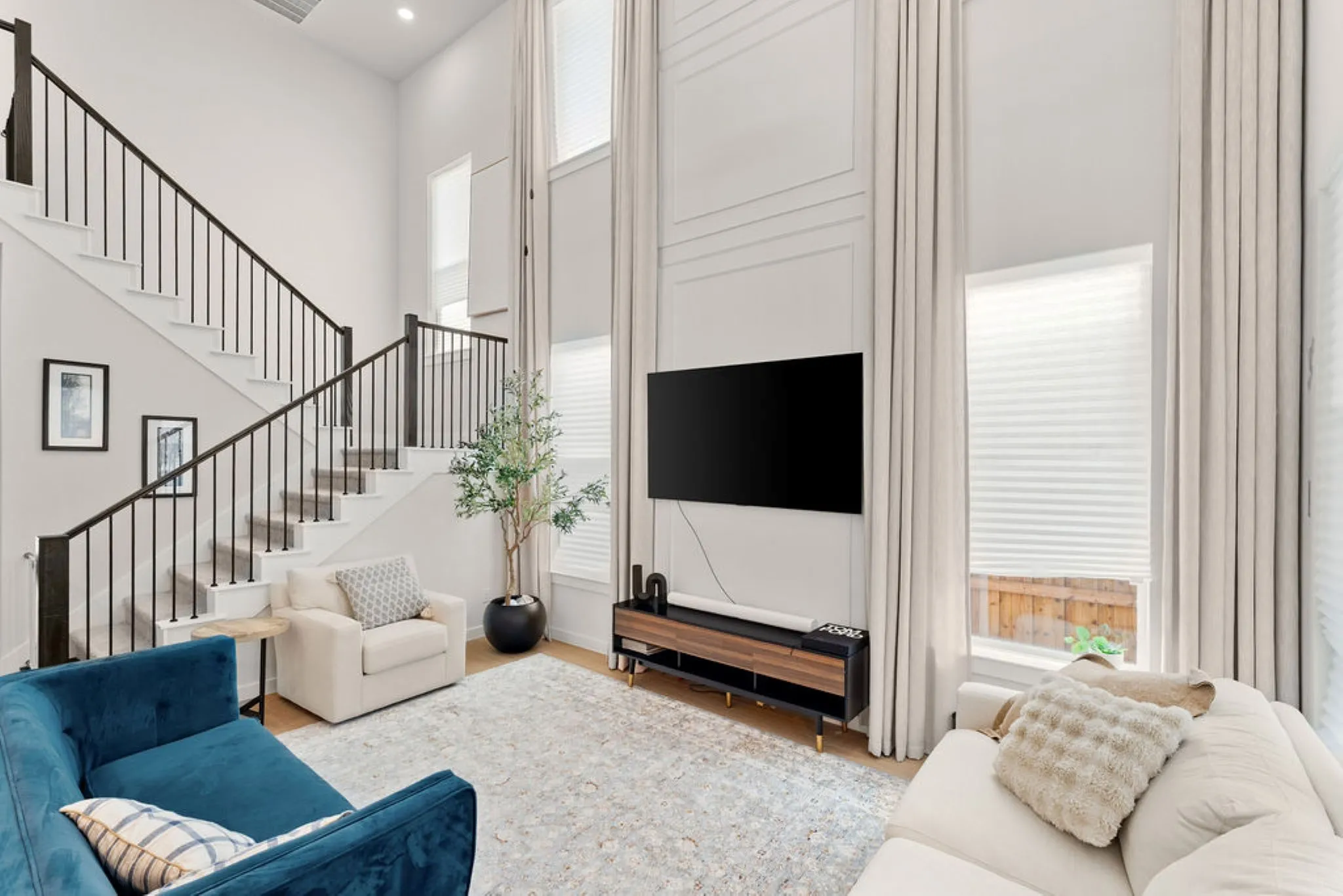 Two-story living area featuring a prominent staircase with dark wood newel posts and black metal balusters