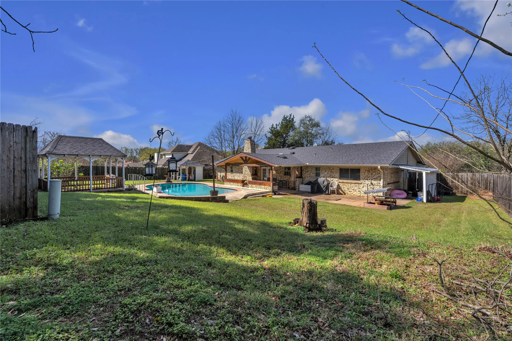 Expansive backyard featuring an inground swimming pool, a dedicated gazebo, and multiple patio areas