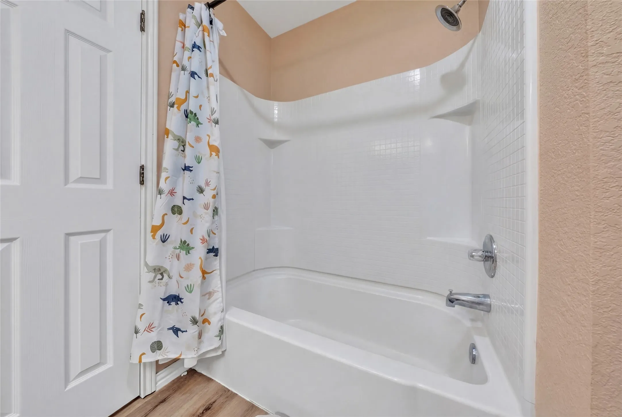 Tub/shower combination featuring white tile-look surround and chrome fixtures