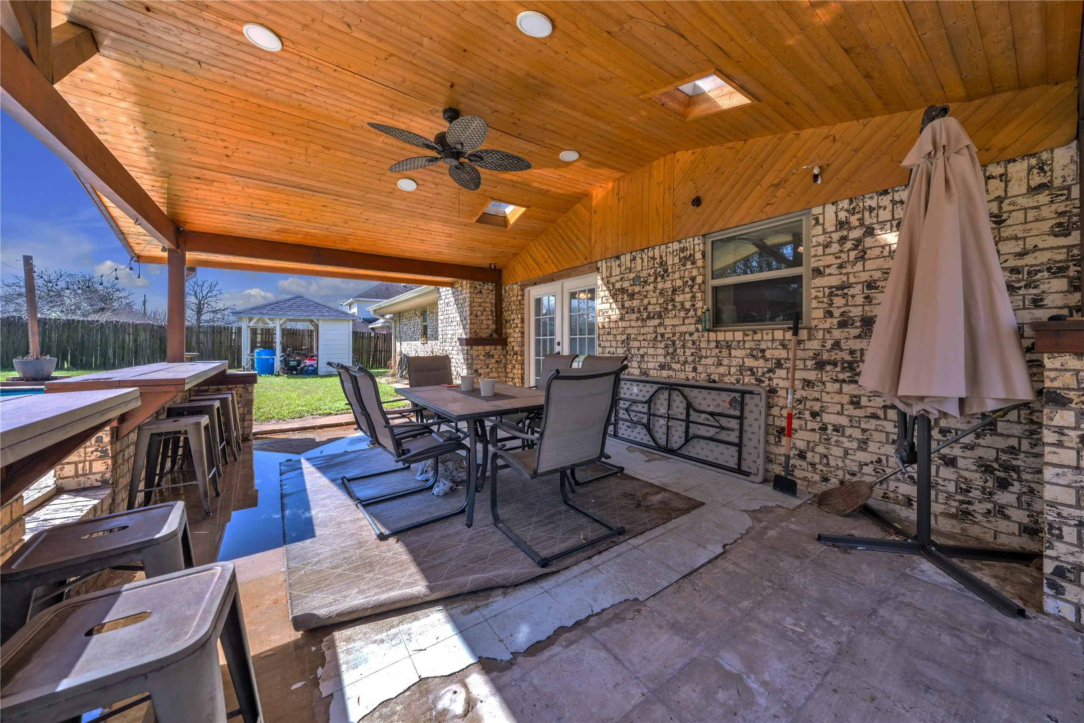 Covered patio featuring a wood-paneled ceiling with recessed lighting and a ceiling fan