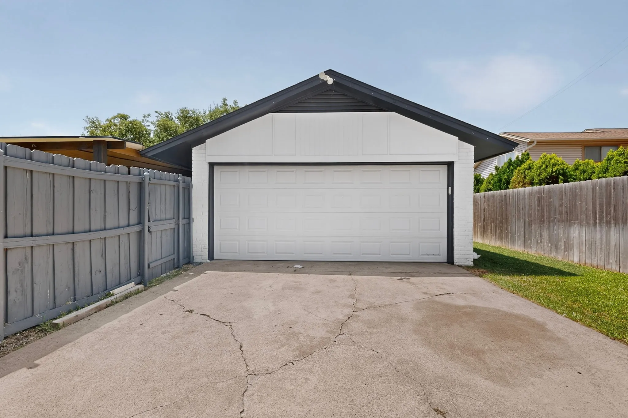 White exterior garage with a paneled door, dark trim, and a concrete driveway