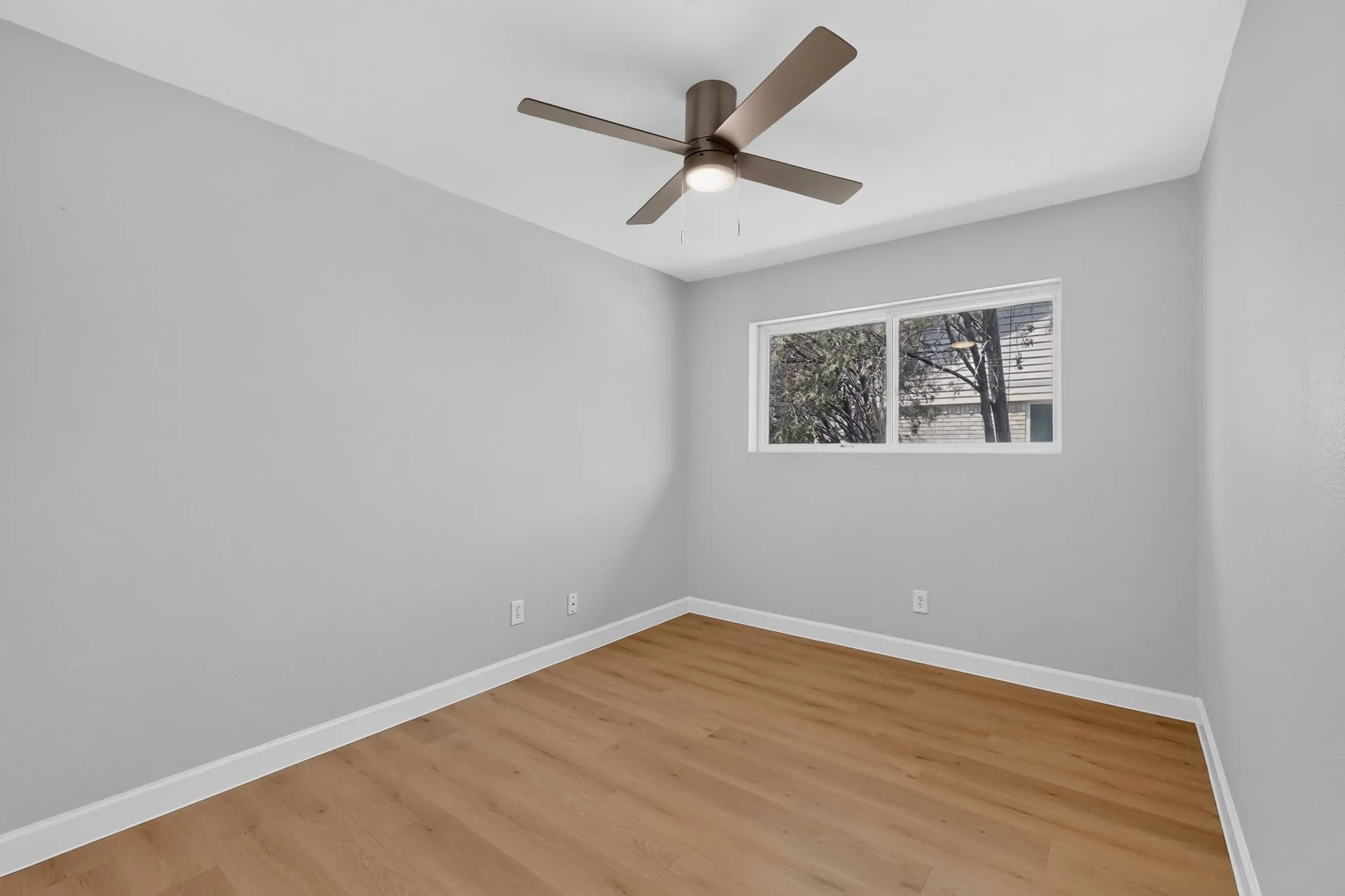 Neutral tone wall paint with crisp white baseboards and wood-finish flooring