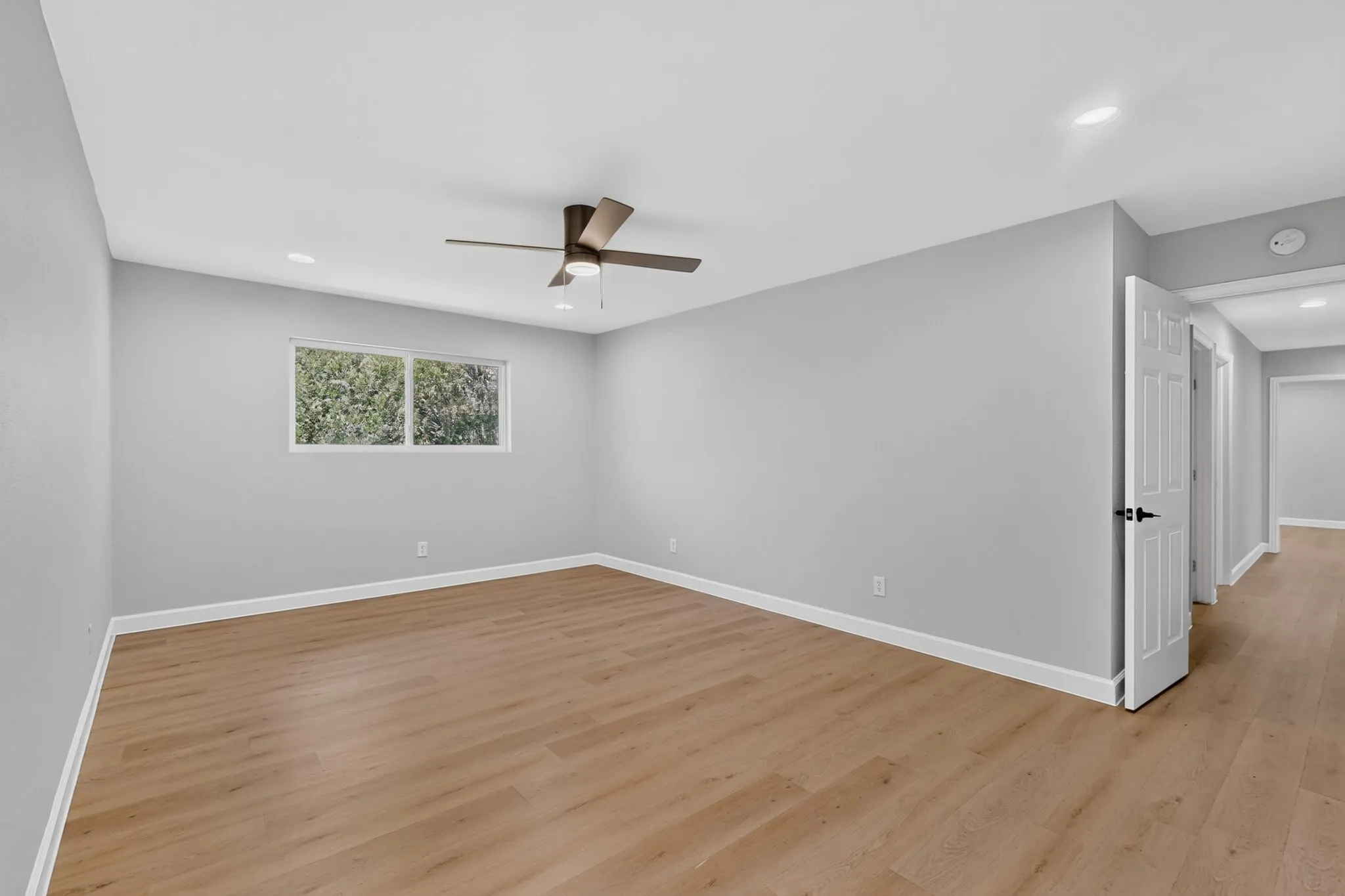 Spacious room featuring wood-finish flooring, light grey walls, and a white ceiling