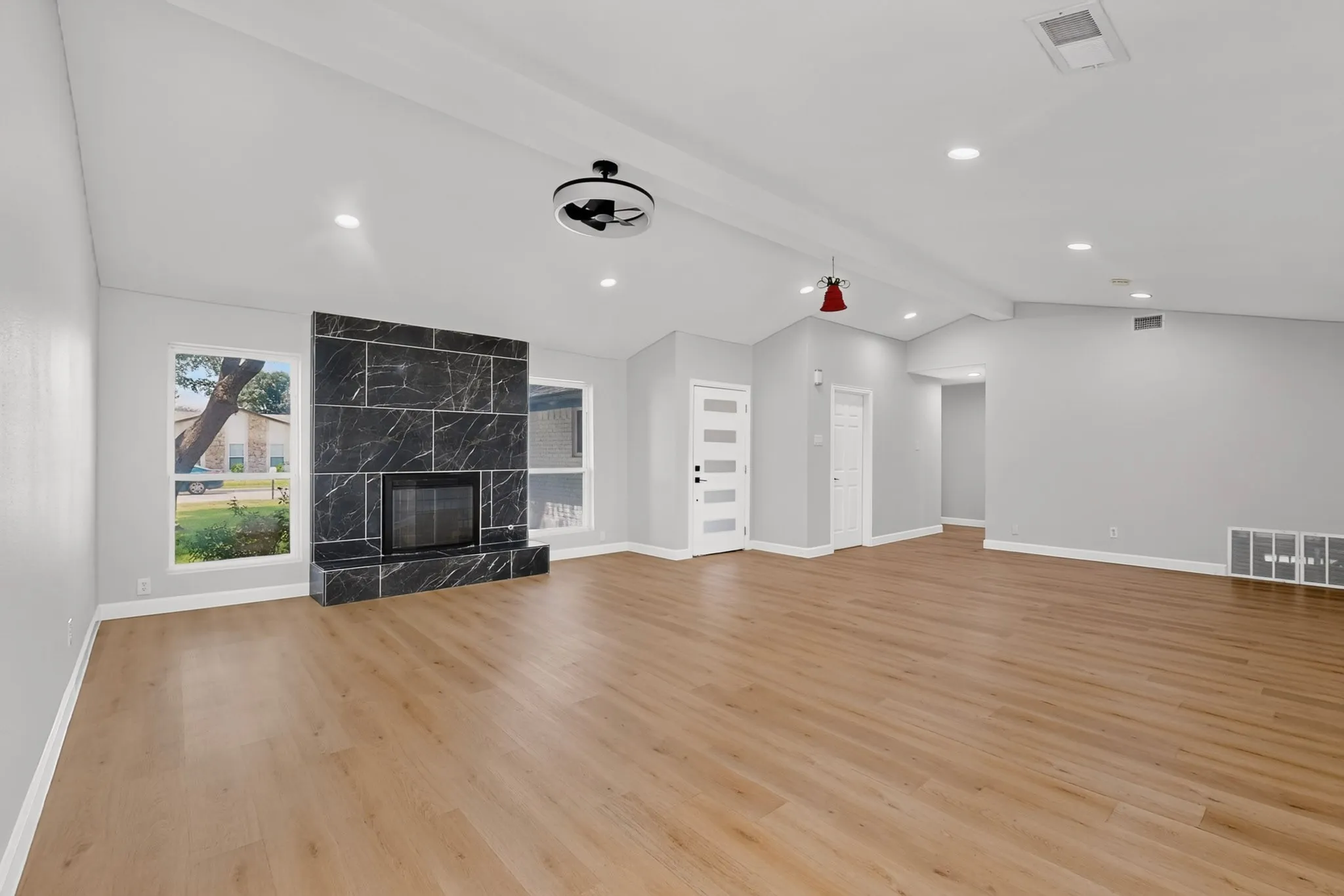 Spacious living area featuring high vaulted ceilings with exposed beams and recessed lighting