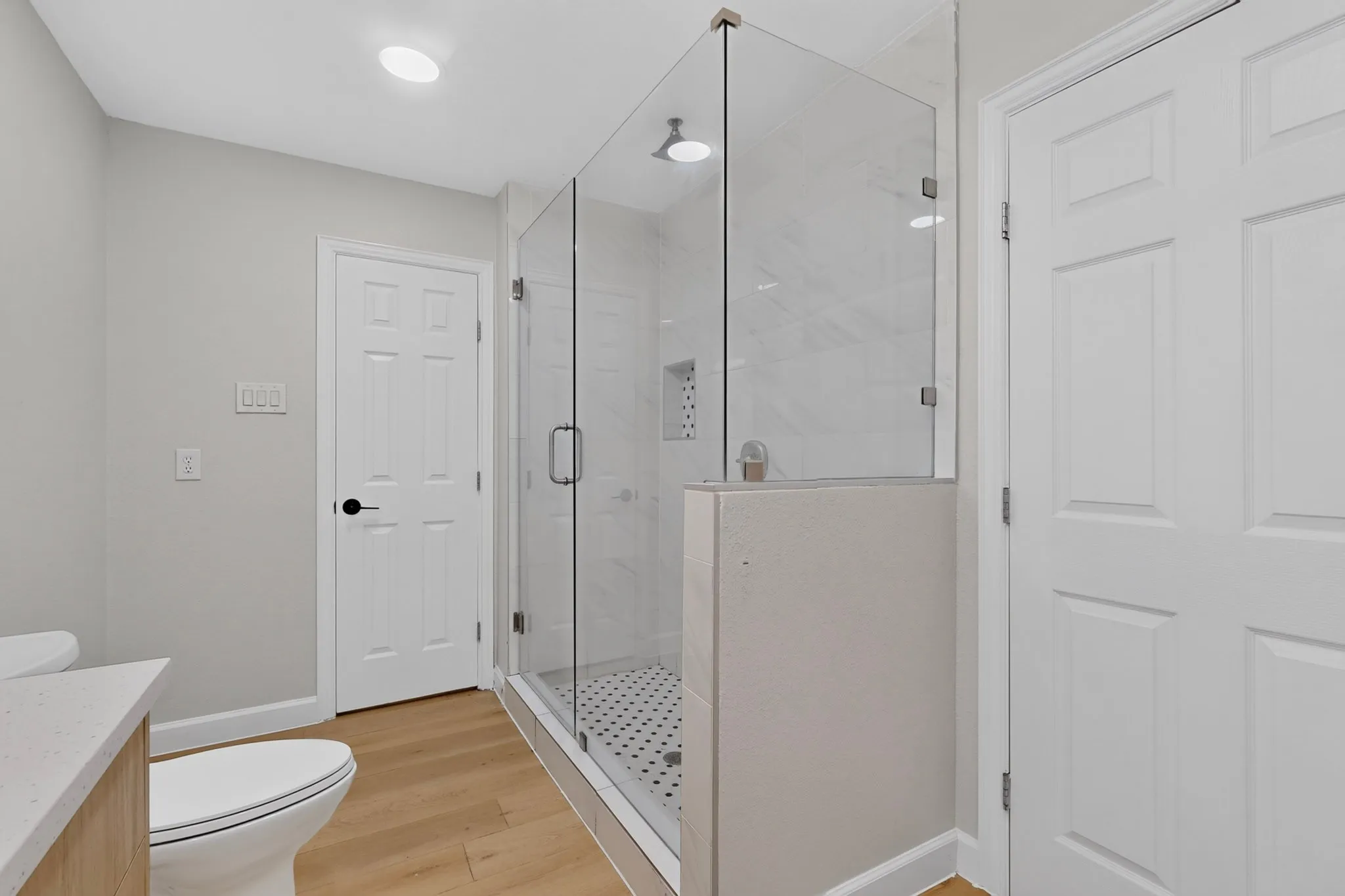 Walk-in shower with clear glass enclosure and black and white penny tile flooring