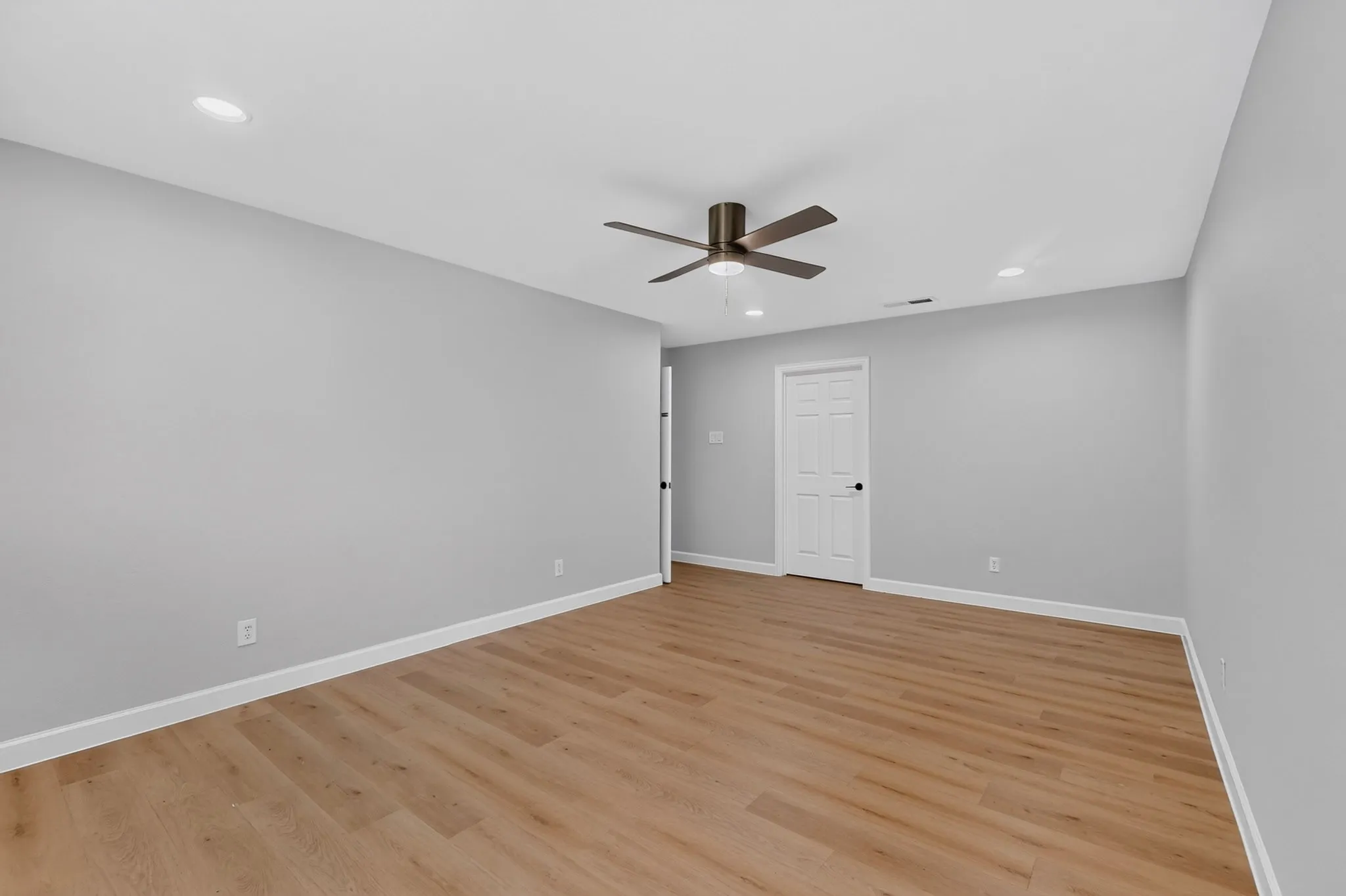 Spacious interior room featuring wood-finish flooring, recessed lighting, and a ceiling fan