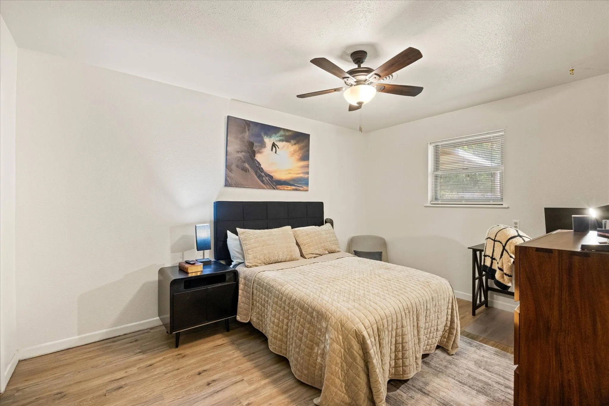 Neutral wall colors featuring wood-finish flooring, a built-in ceiling fan with integrated lighting, and a single window with blinds