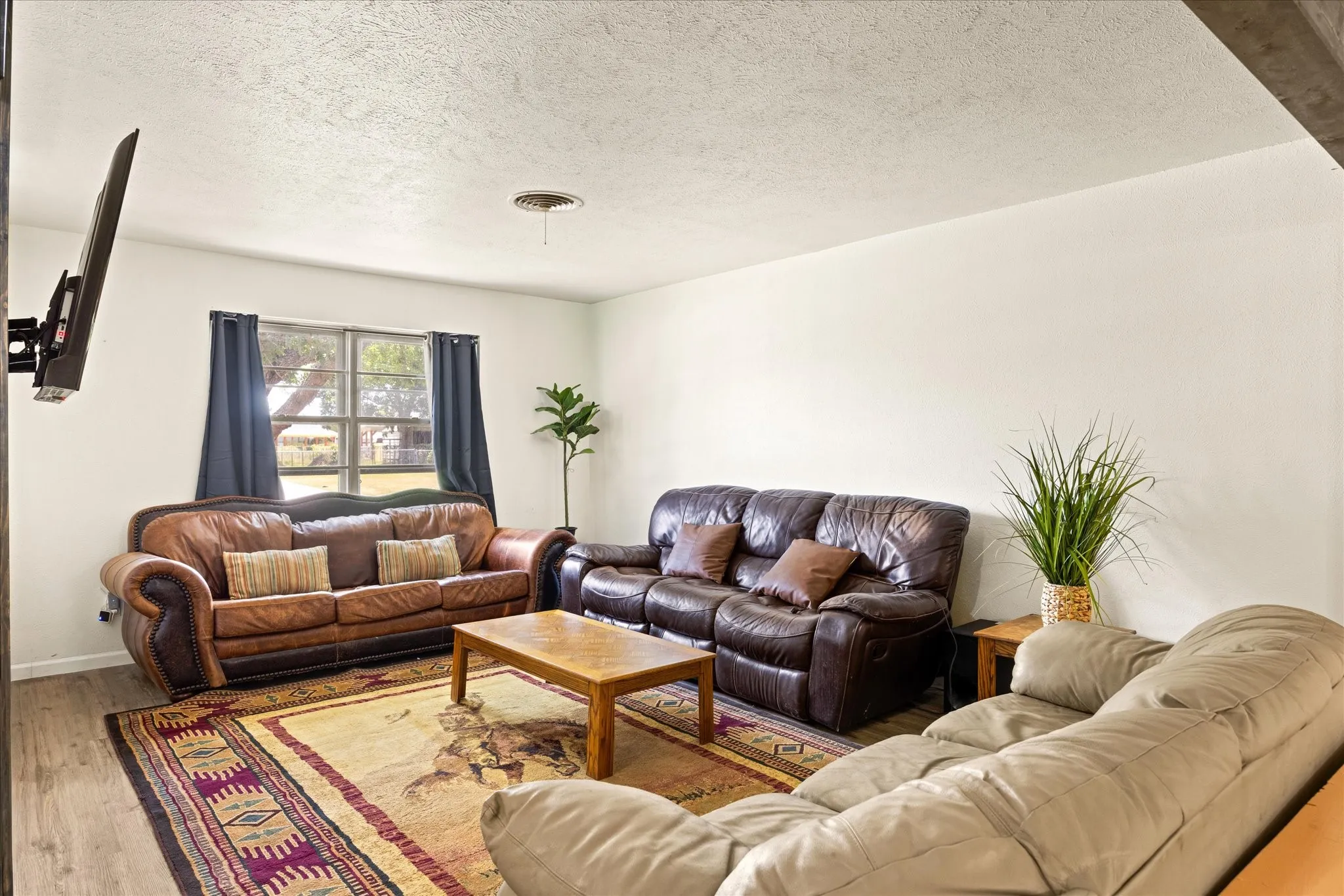 Living area featuring neutral wall tones, wood-finish flooring, and a ceiling-mounted light fixture