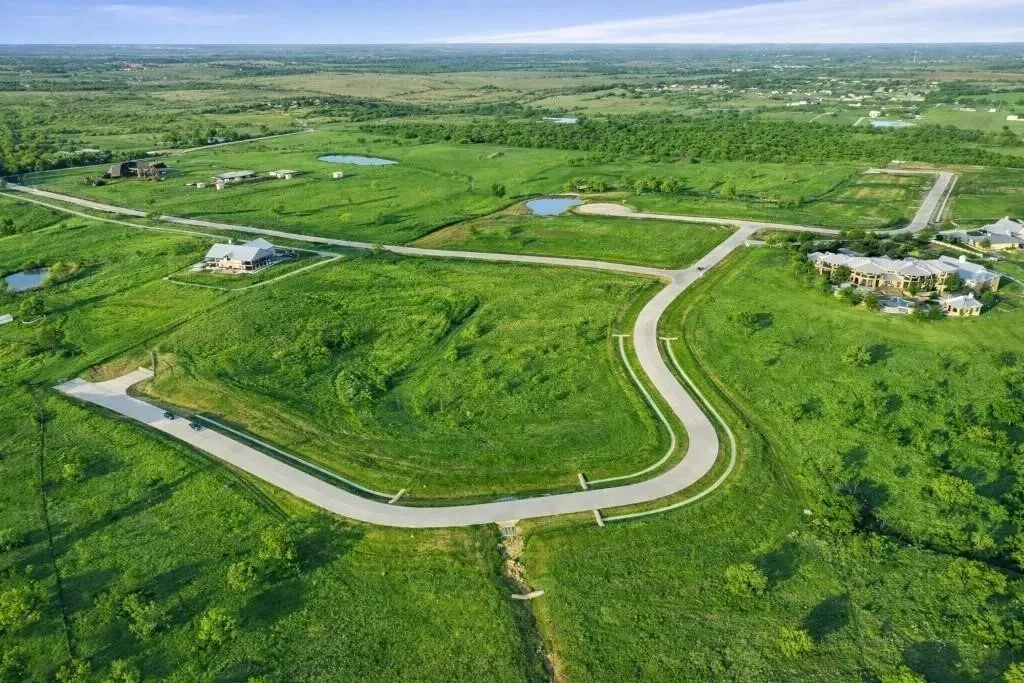 Expansive green landscape featuring winding paved roads and multiple developed lots