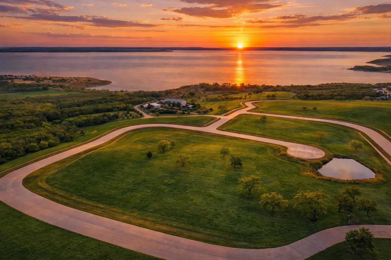 Expansive waterfront property featuring paved roads, manicured green spaces, and a private pond