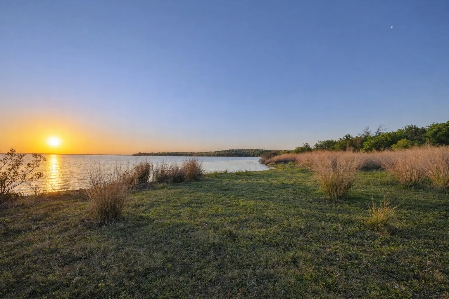 Expansive waterfront property featuring a wide body of water, natural shoreline, and mature trees