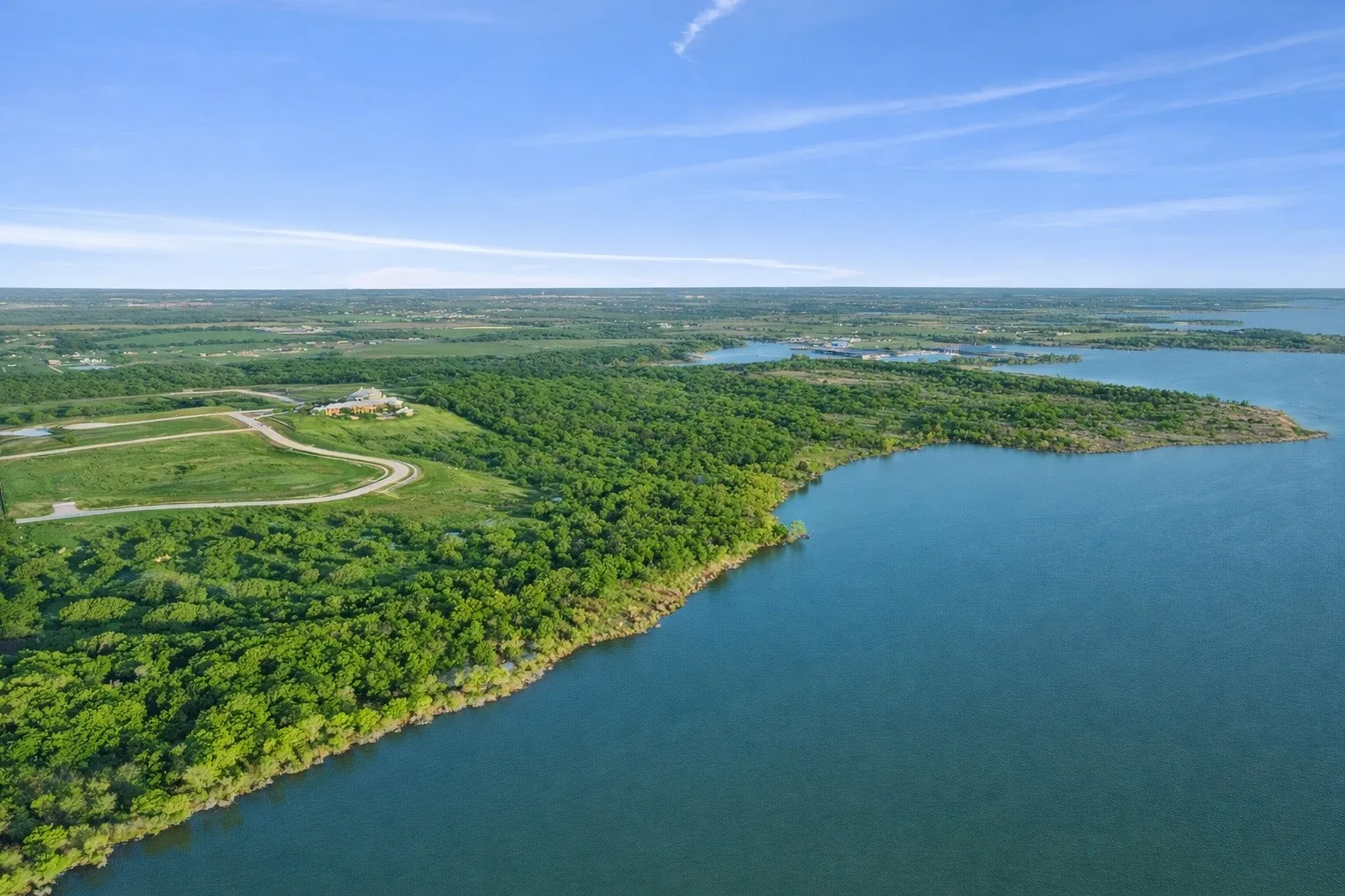 Expansive water frontage property featuring a verdant landscape, a large body of water, and a prominent landmass extending into the water