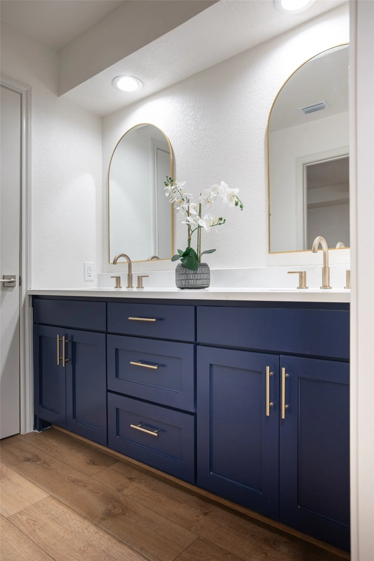 Updated bath featuring a brand-new vanity with white quartz countertop, elegant gold fixtures, new mirrors, and updated lighting.