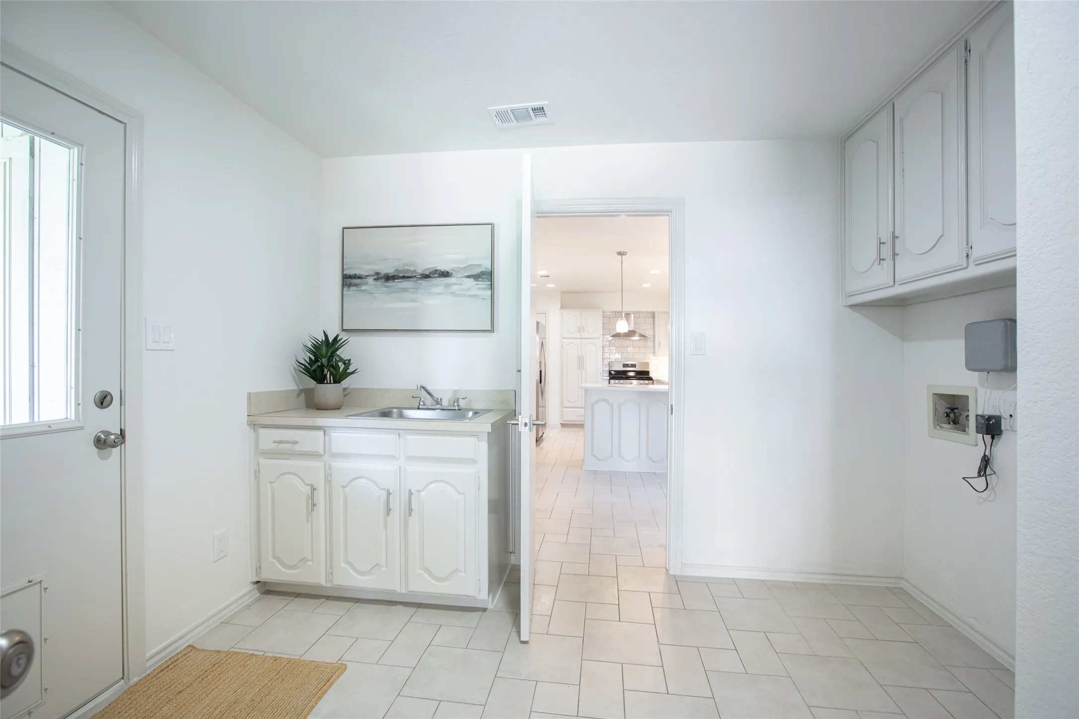 Spacious utility room featuring a sink with ample cabinetry, full-size washer and dryer space, and two additional closets for exceptional storage.