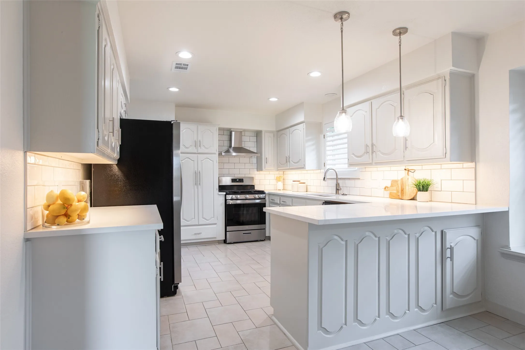 Updated kitchen featuring freshly painted cabinetry, white quartz countertops, new backsplash, new gas range, updated lighting, new cabinet hardware, and new faucet.