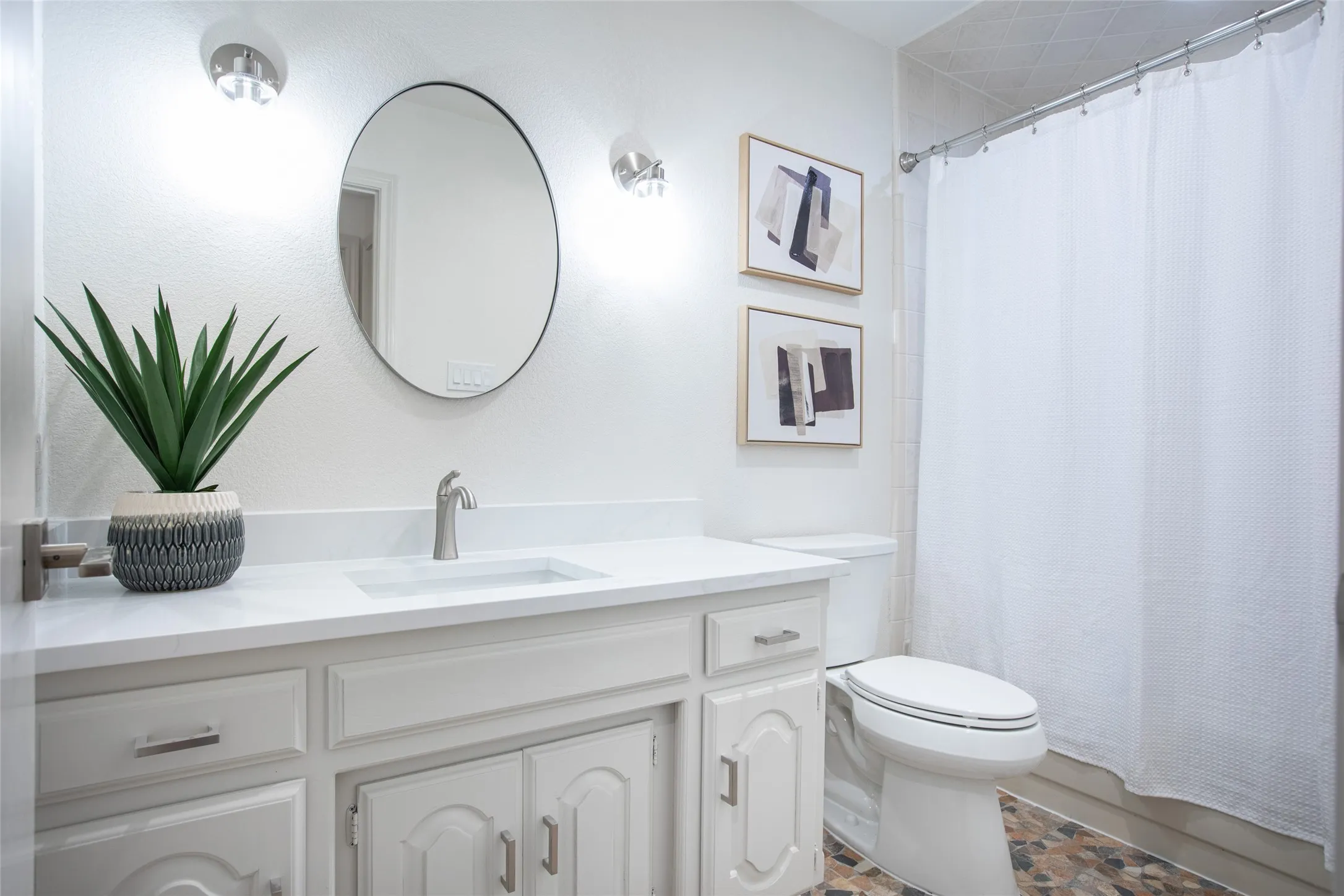 Updated secondary bathroom featuring freshly painted walls and cabinetry, new white quartz countertop, new mirror and lighting, and new faucets.