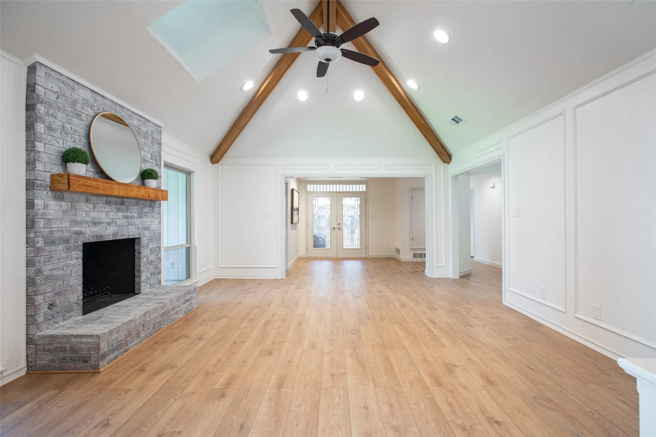 Light-filled living room featuring new windows and a skylight for abundant natural light, complemented by beautiful wood ceiling beams that add warmth and character.