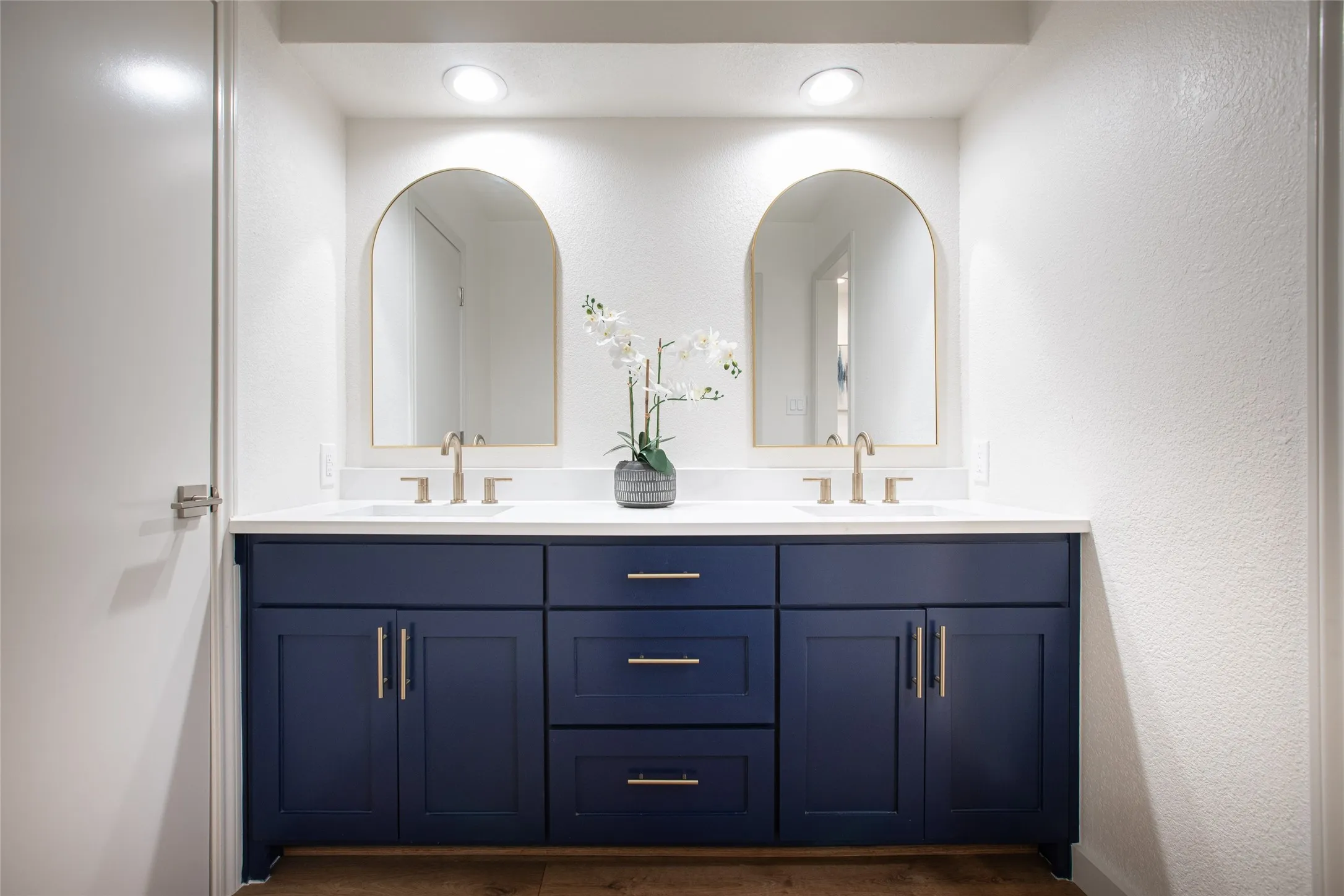 Updated bath featuring a brand-new vanity with white quartz countertop, elegant gold fixtures, new mirrors, and updated lighting.