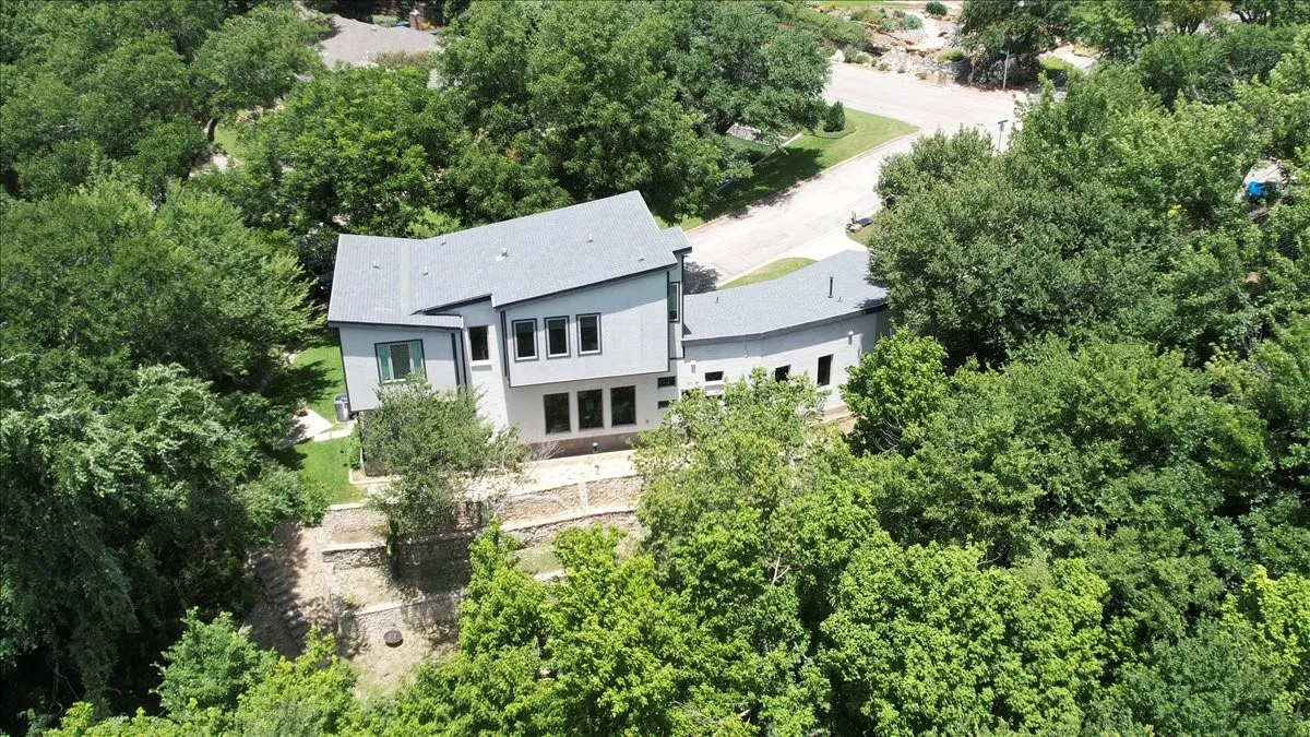 Contemporary architectural design with a multi-level roofline, light gray siding, and multiple window arrangements