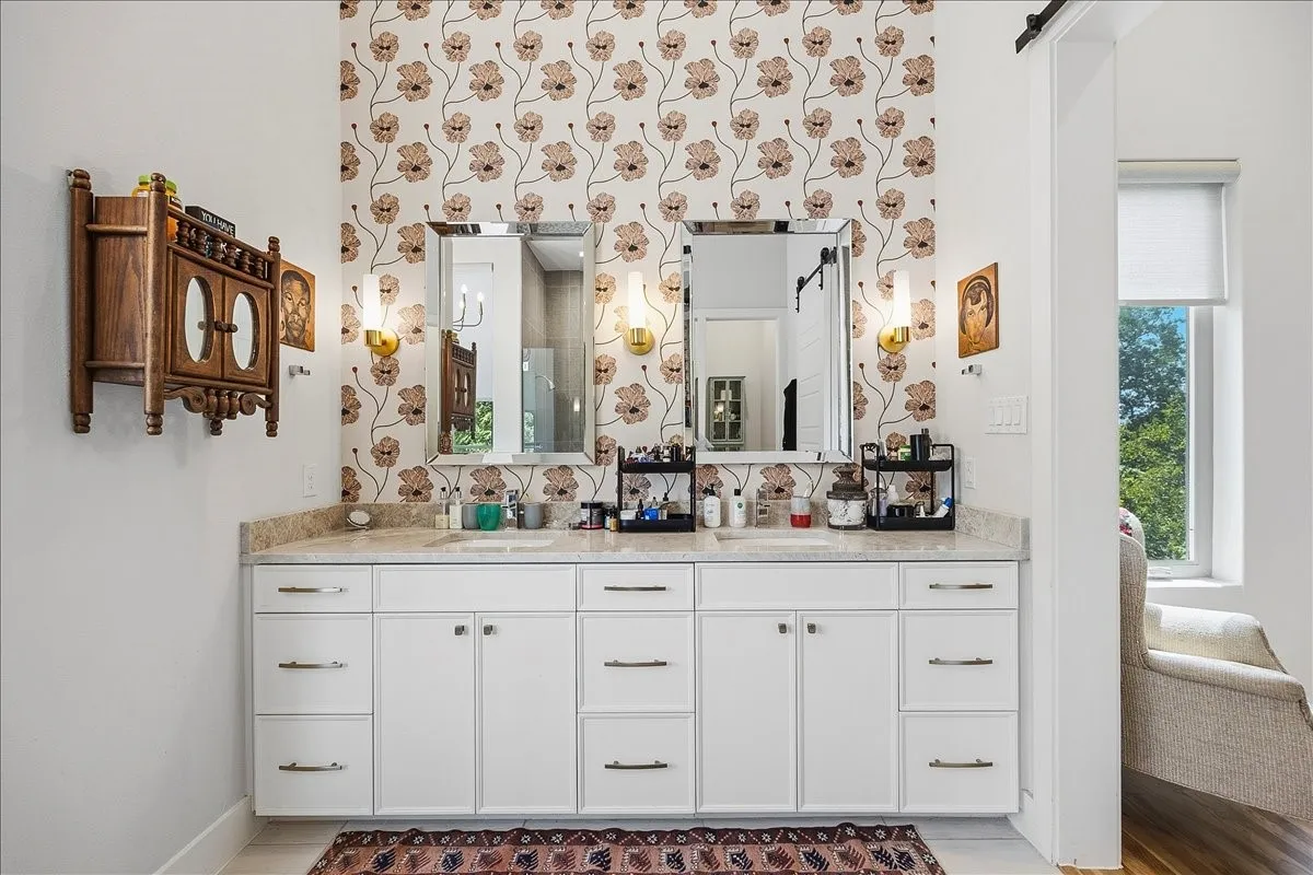 Double vanity with stone countertop, dual undermount sinks, and wall-mounted sconce lighting