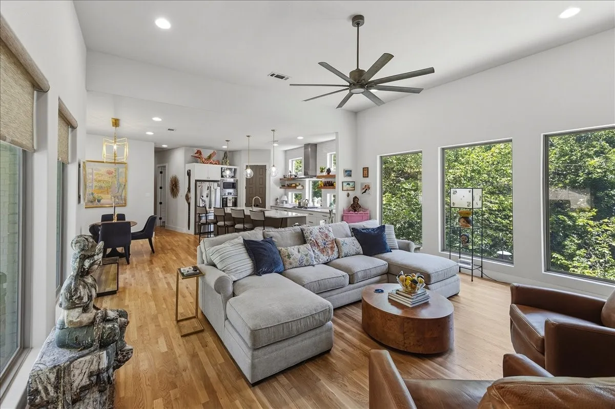 Open-concept living area featuring high ceilings, wood-finish flooring, recessed lighting, and a modern ceiling fan