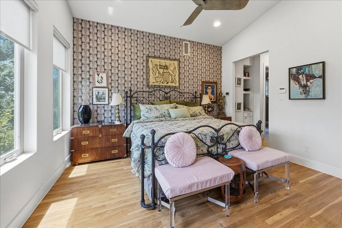 Accent wall with patterned wallpaper, vaulted ceiling, wood-finish flooring, recessed lighting, and large windows