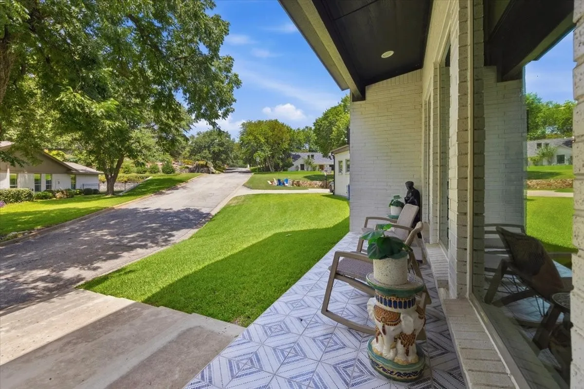 Inviting front porch featuring a patterned tile floor, white brick facade, and a dark soffit